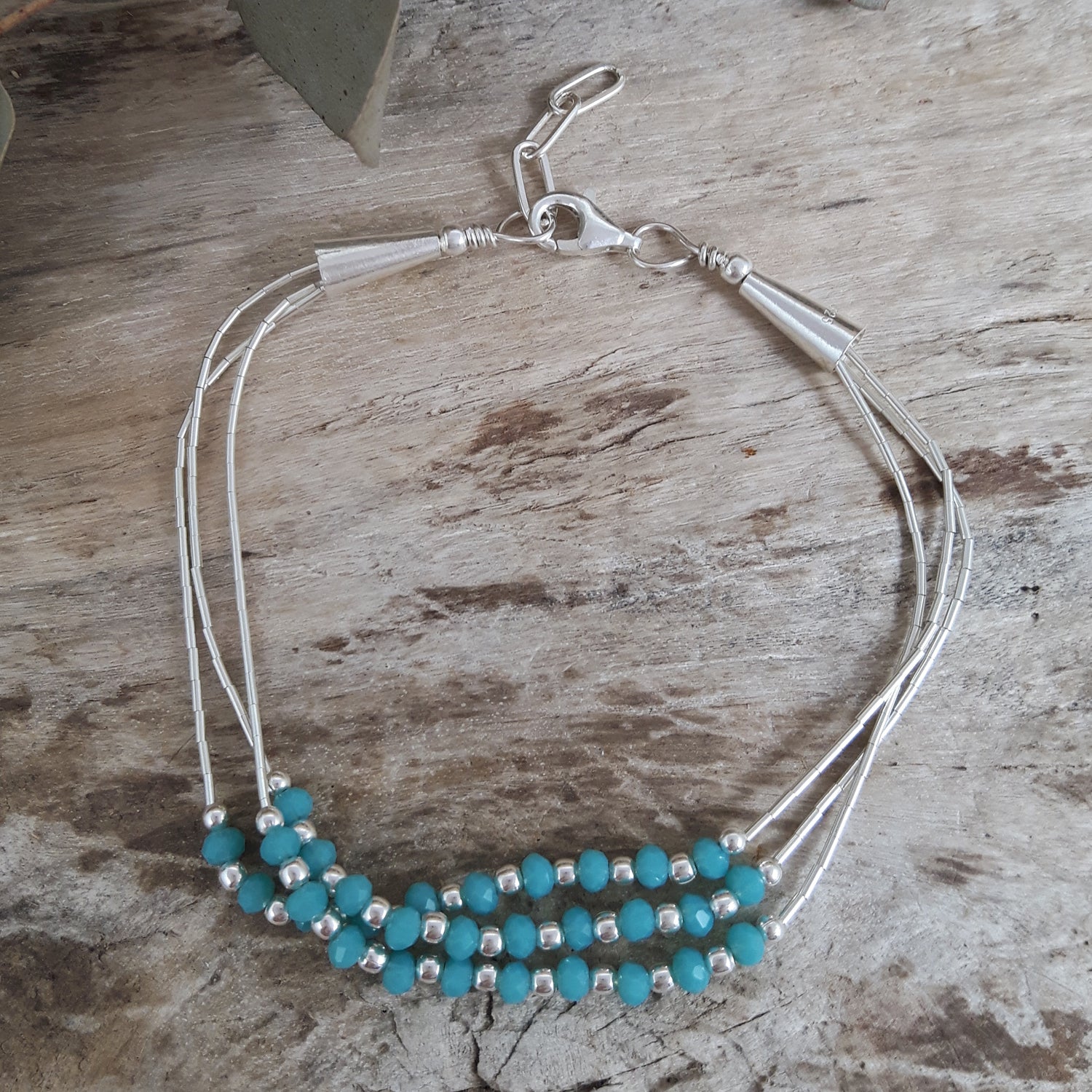 Bracelet with blue chalcedony beads and sterling silver accents on a wooden surface