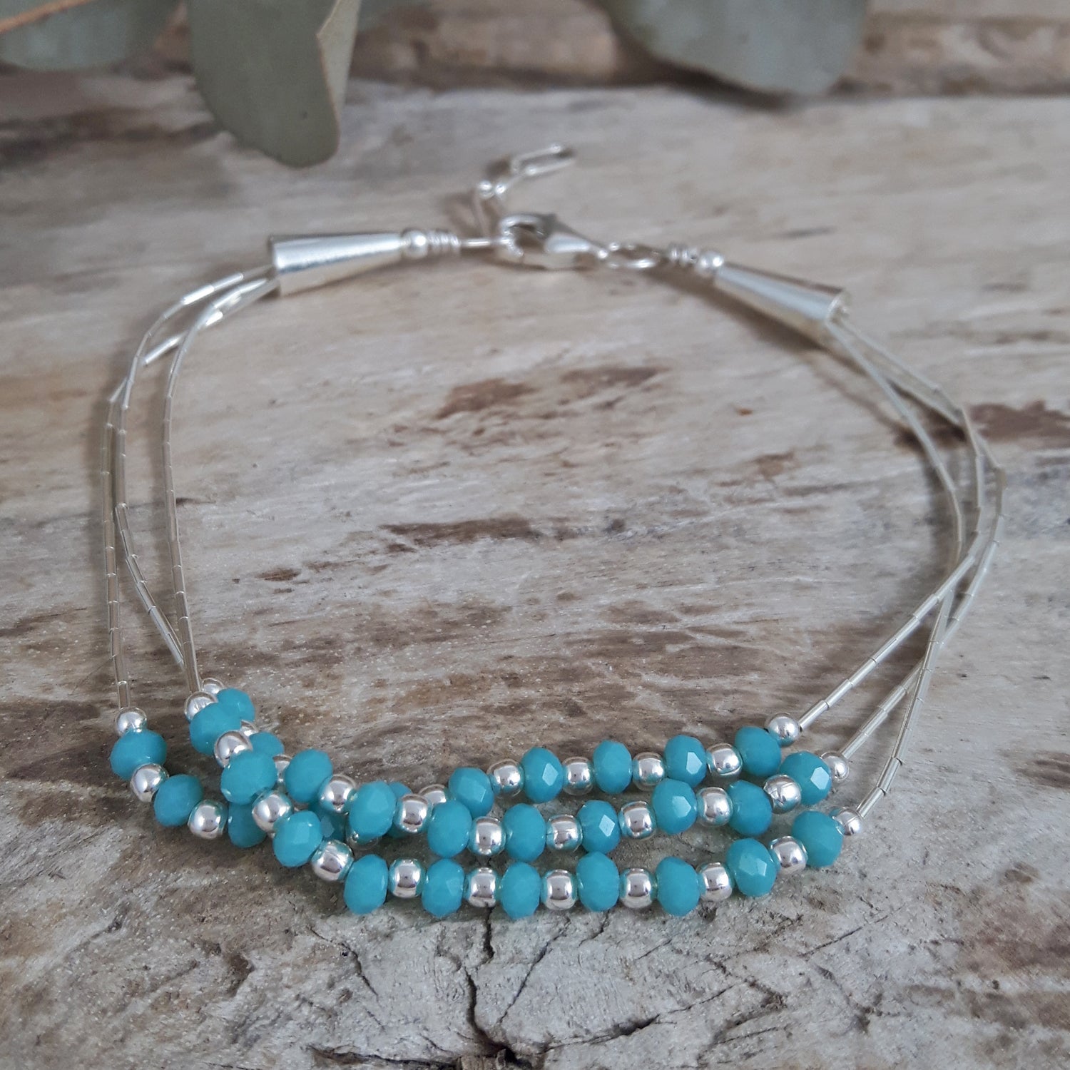 Blue chalcedony beaded bracelet with sterling silver accents on a wooden surface