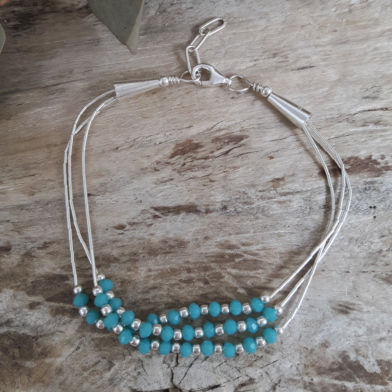 Bracelet with blue chalcedony beads and sterling silver accents on a wooden surface