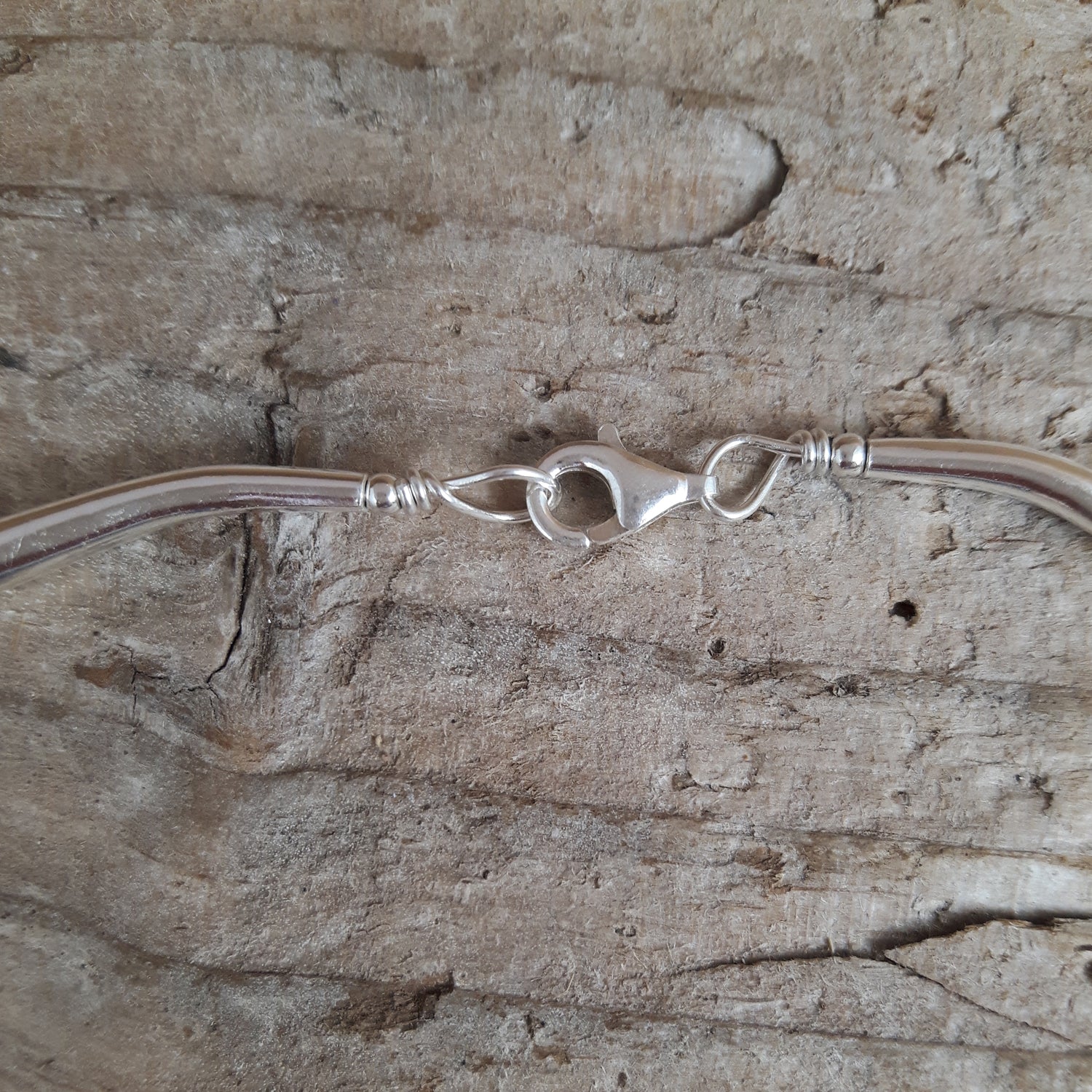 Sterling silver necklace with a clasp on a wooden surface