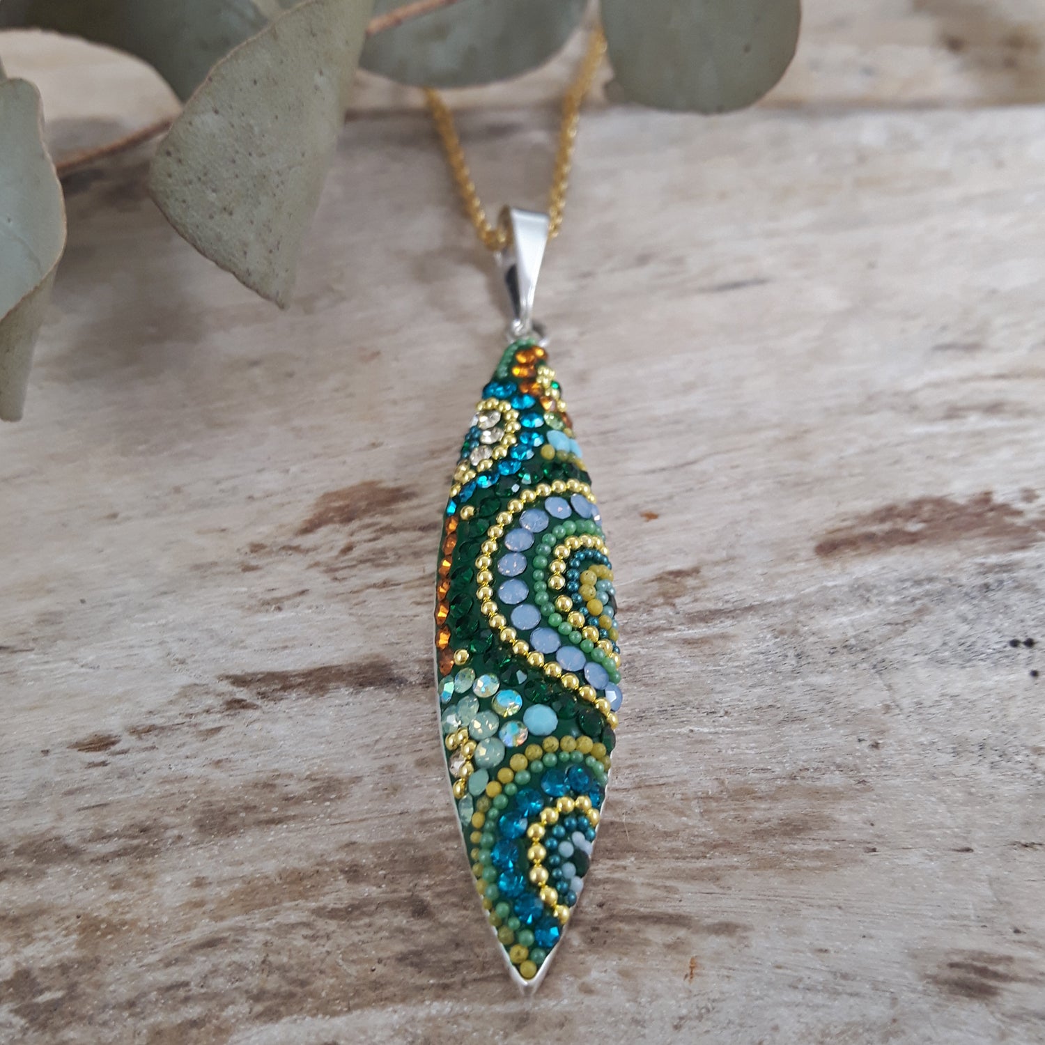 Decorative micro-bead and crystal pendant with intricate pattern on a wooden surface