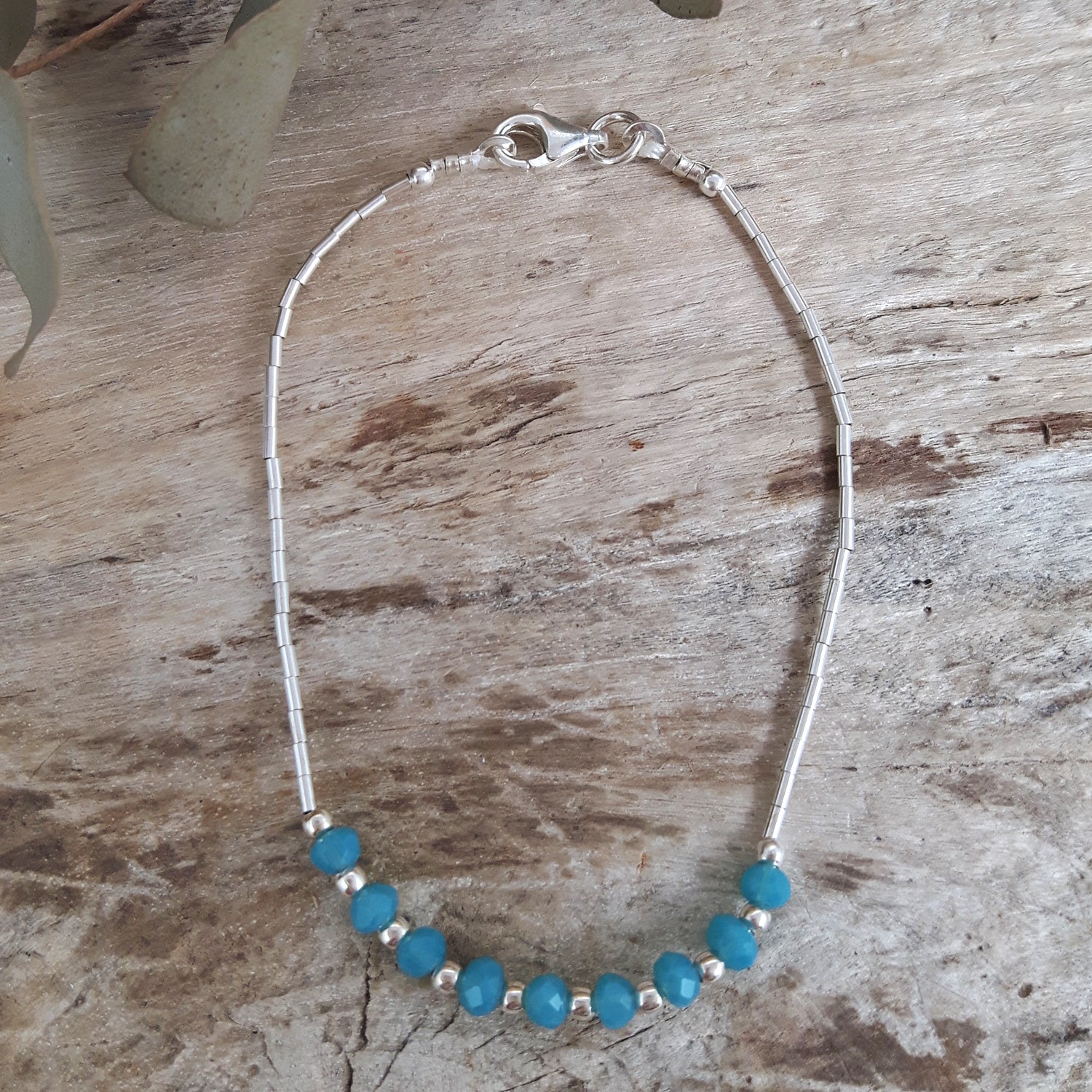 Silver bracelet with blue chalcedony beads on a wooden surface