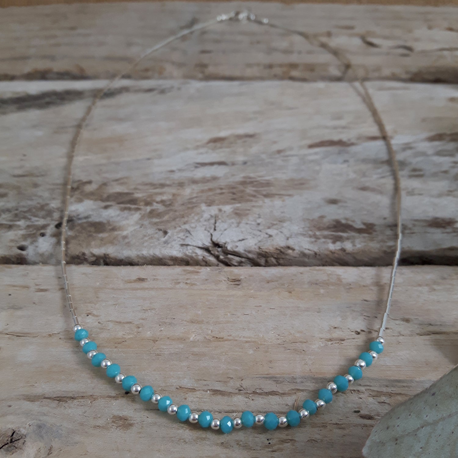 Necklace with blue chalcedony beads and sterling silver accents on a wooden surface