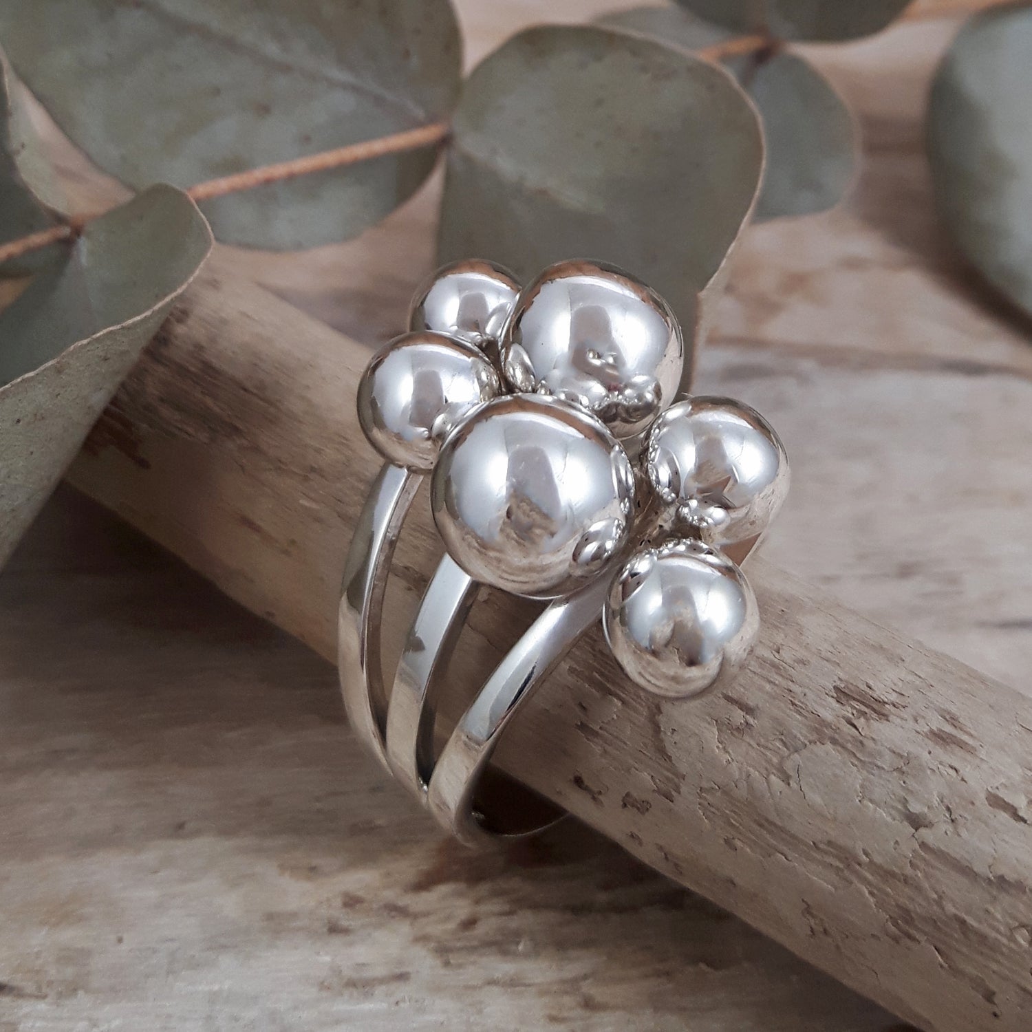 Sterling silver ring with spherical design on a wooden surface with leaves