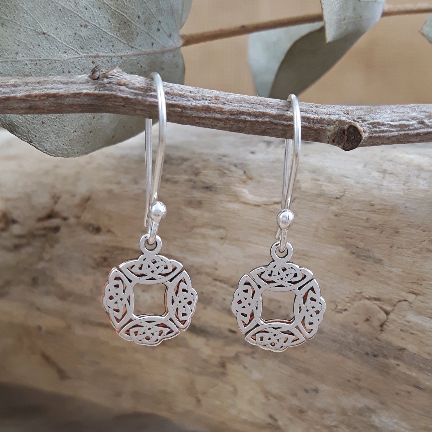 Sterling silver & copper celtic drop earrings hanging on a branch with a natural background