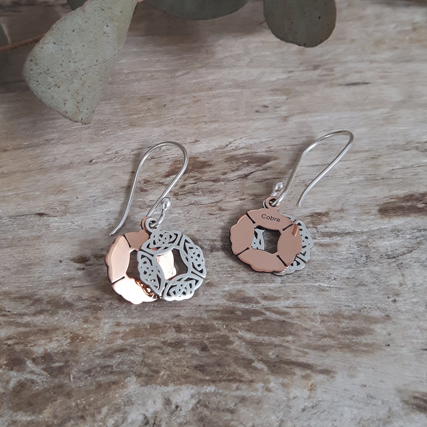 Pair of sterling silver and copper earrings on a wooden surface