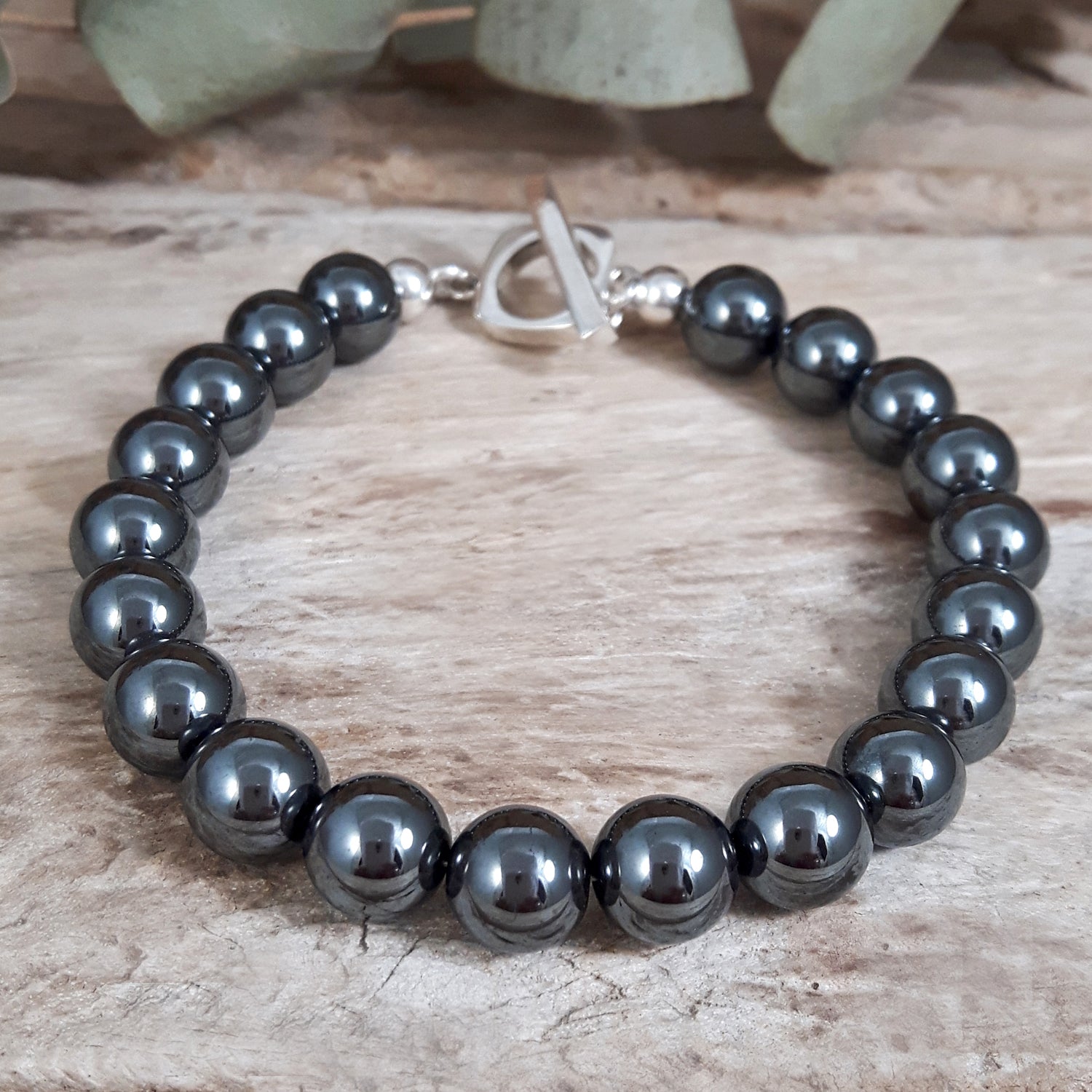 Black hematite beaded bracelet with silver clasp on a wooden surface