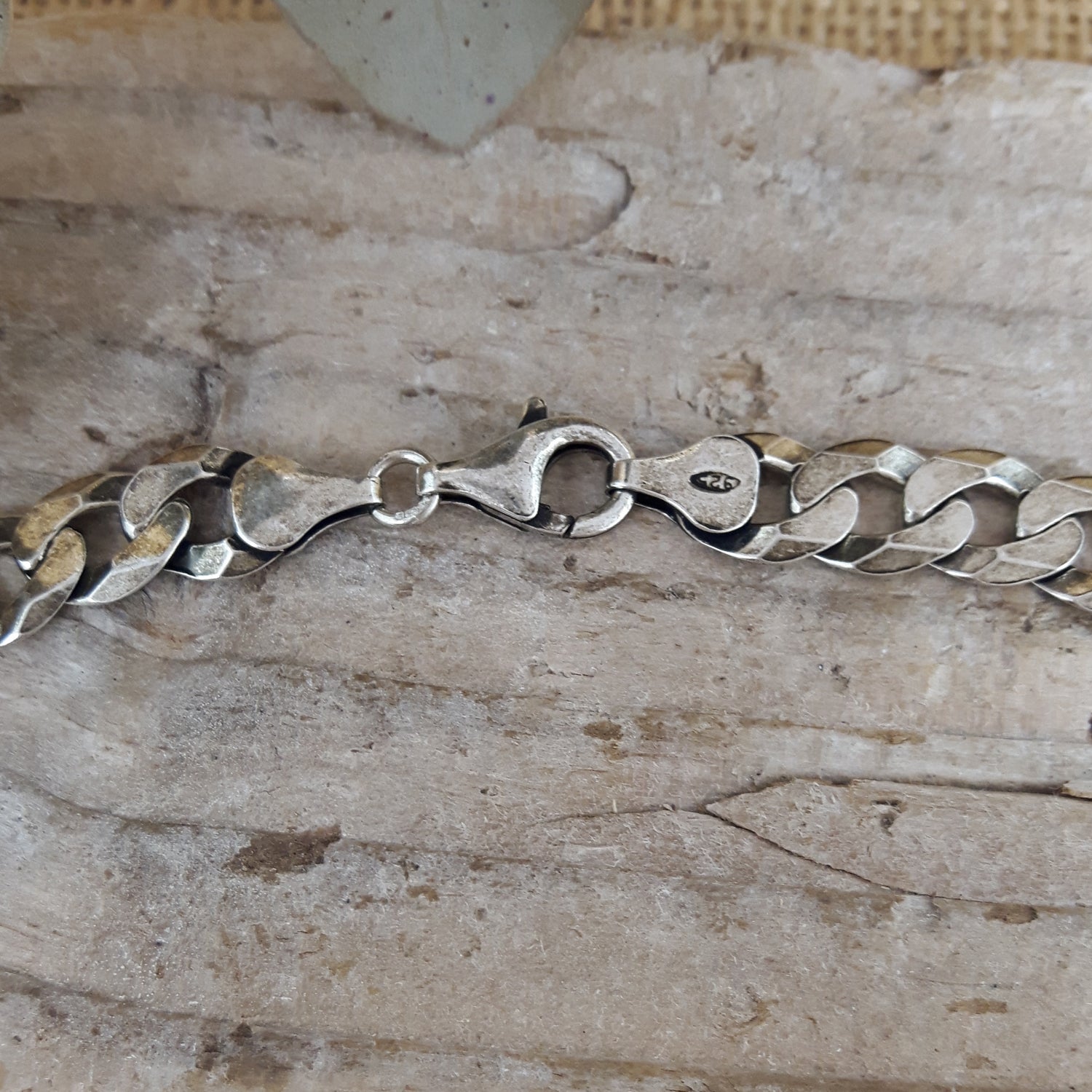 Sterling silver chain bracelet on a textured driftwood surface