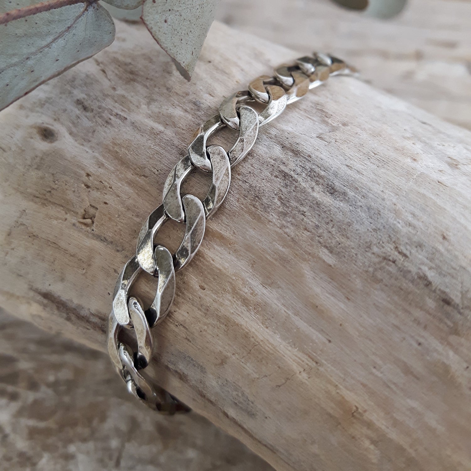Oxidised sterling silver chain bracelet on a wooden surface with a natural background