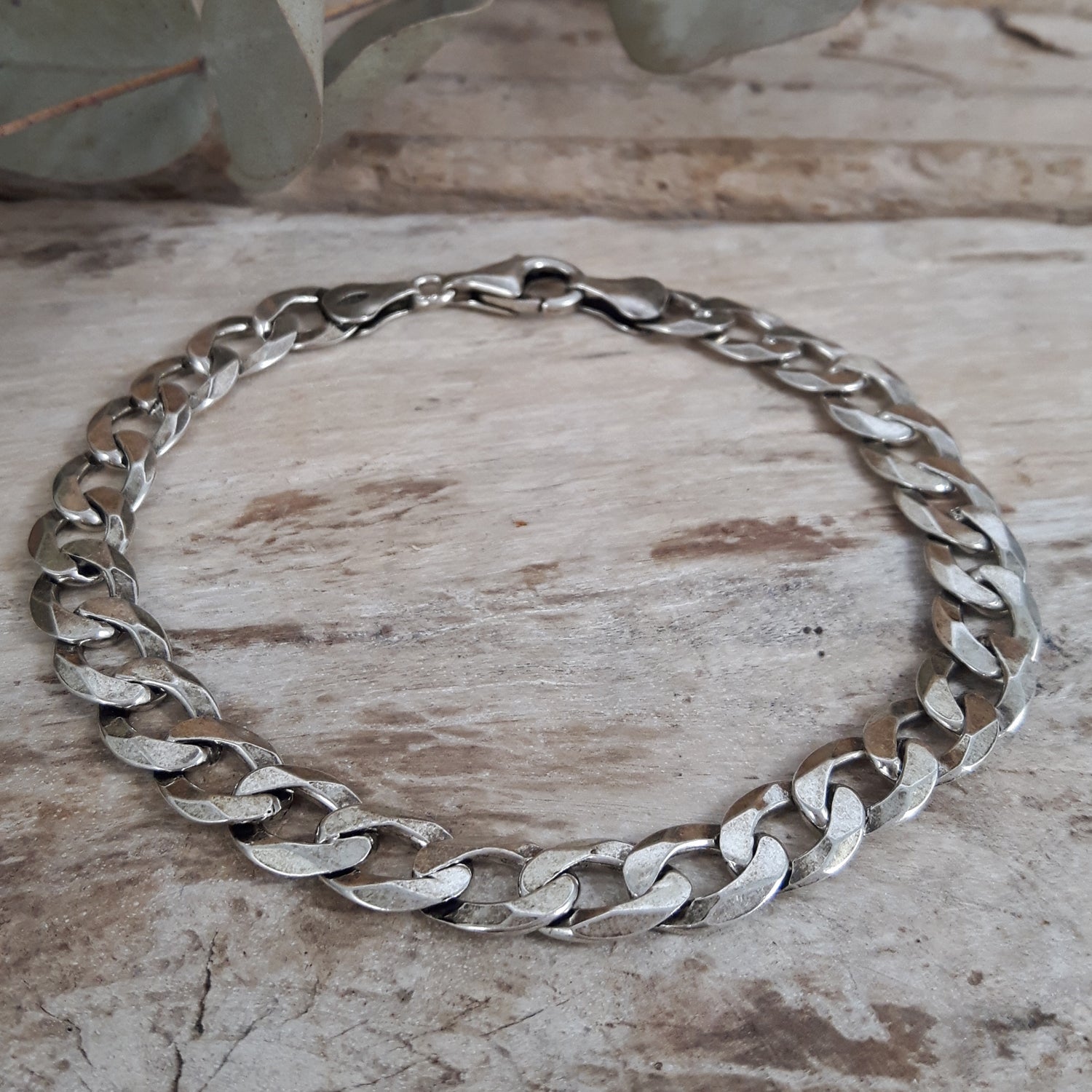 Mens oxidised sterling silver chain necklace on a wooden surface with a plant in the background