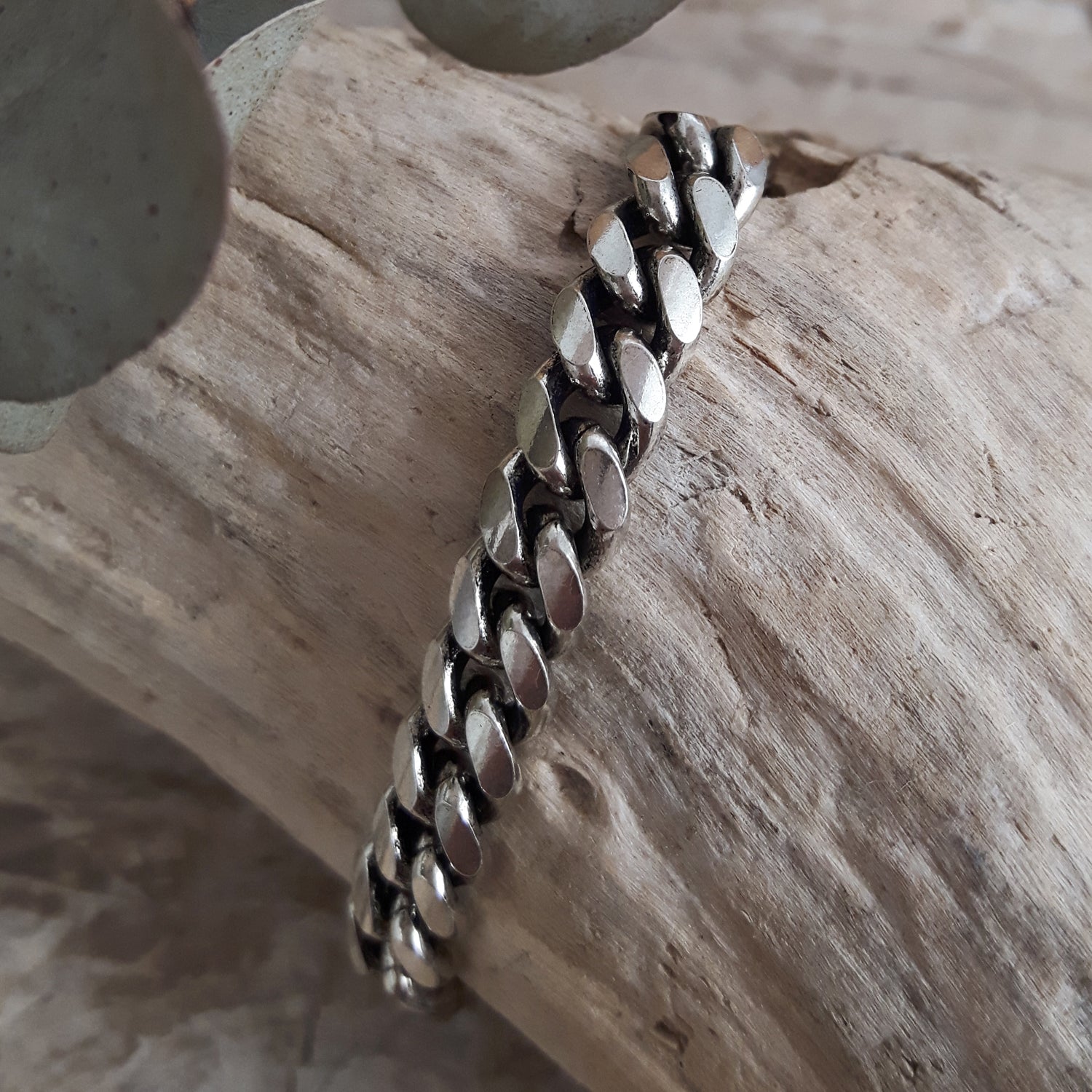 Unisex sterling silver cuban chain bracelet on a wooden surface