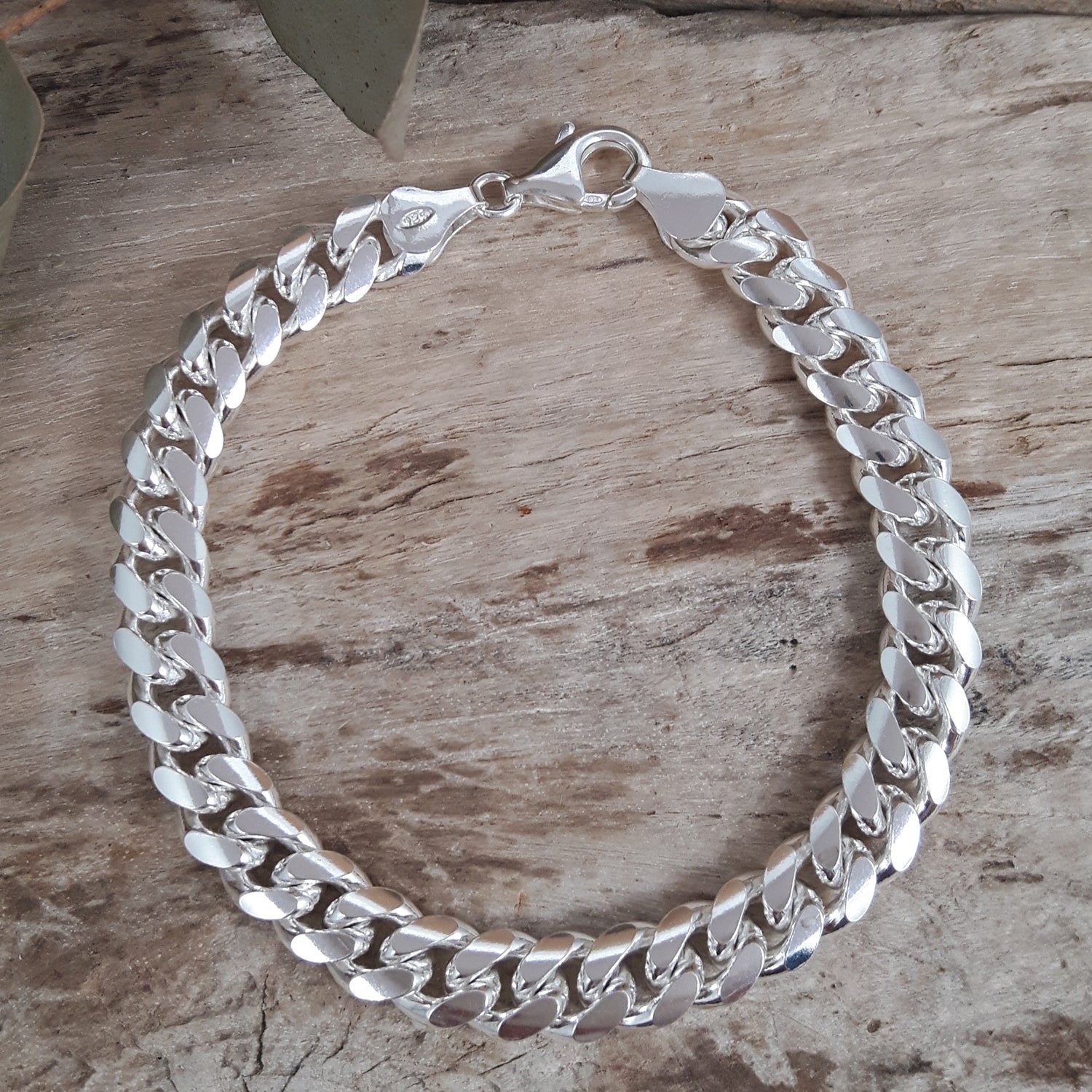 Polished sterling silver chain bracelet on a wooden surface