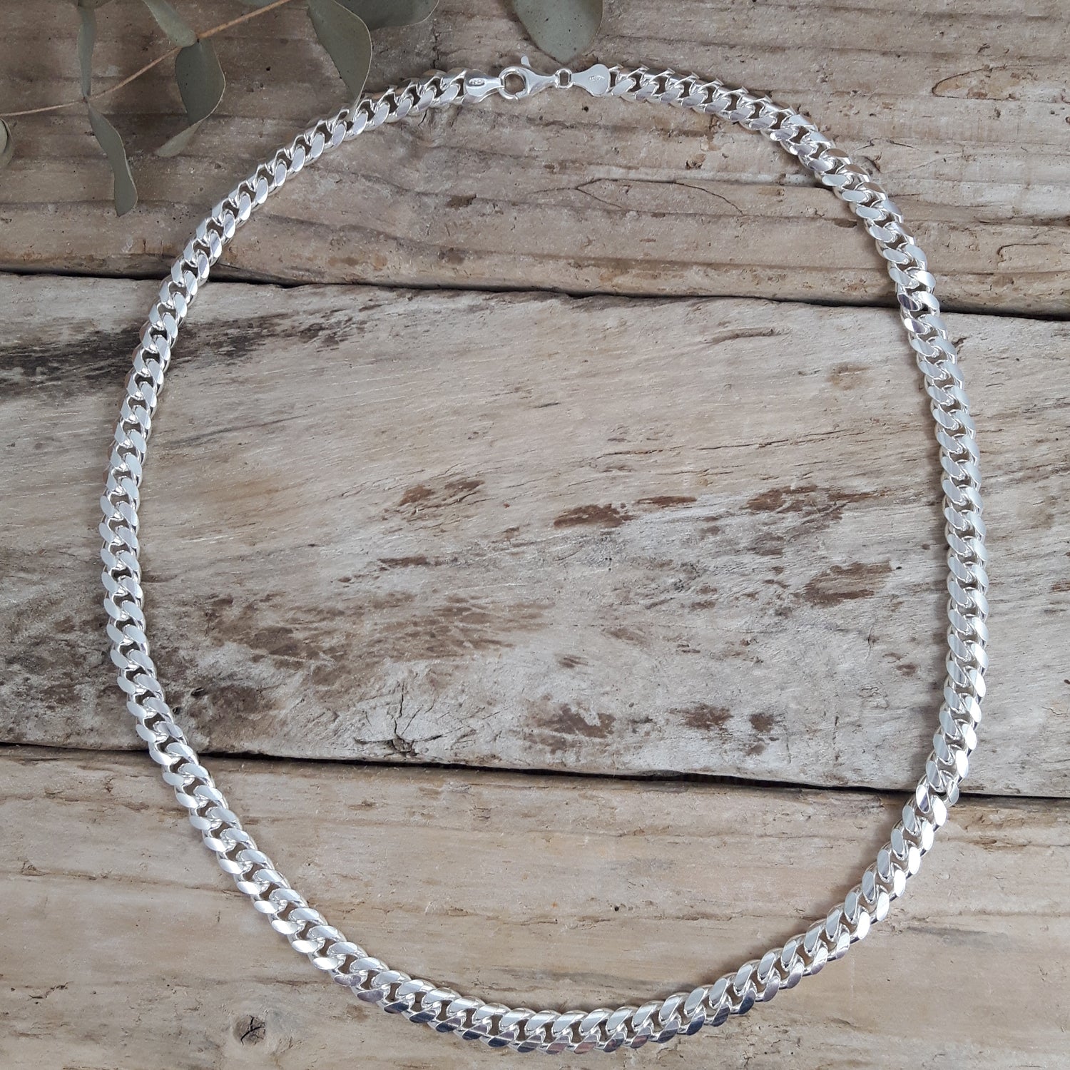 Polished sterling silver chain necklace on a wooden surface
