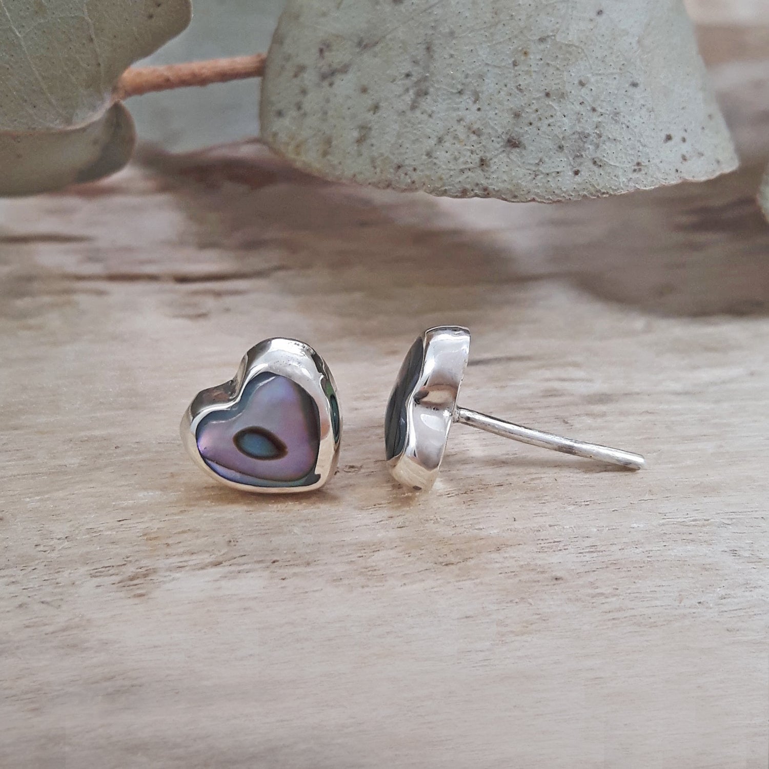 Side profile of 925 sterling silver abalone heart stud earring showing butterfly post fitting, mauve iridescent shell. Back of 925 sterling silver abalone heart stud earrings showing hallmark stamp and stud post