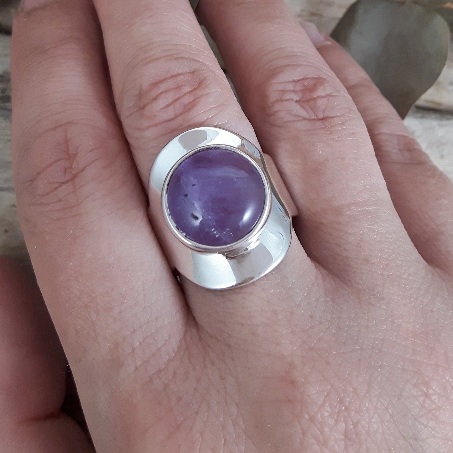 Sterling silver adjustable ring with a purple amethyst gemstone on a person's finger