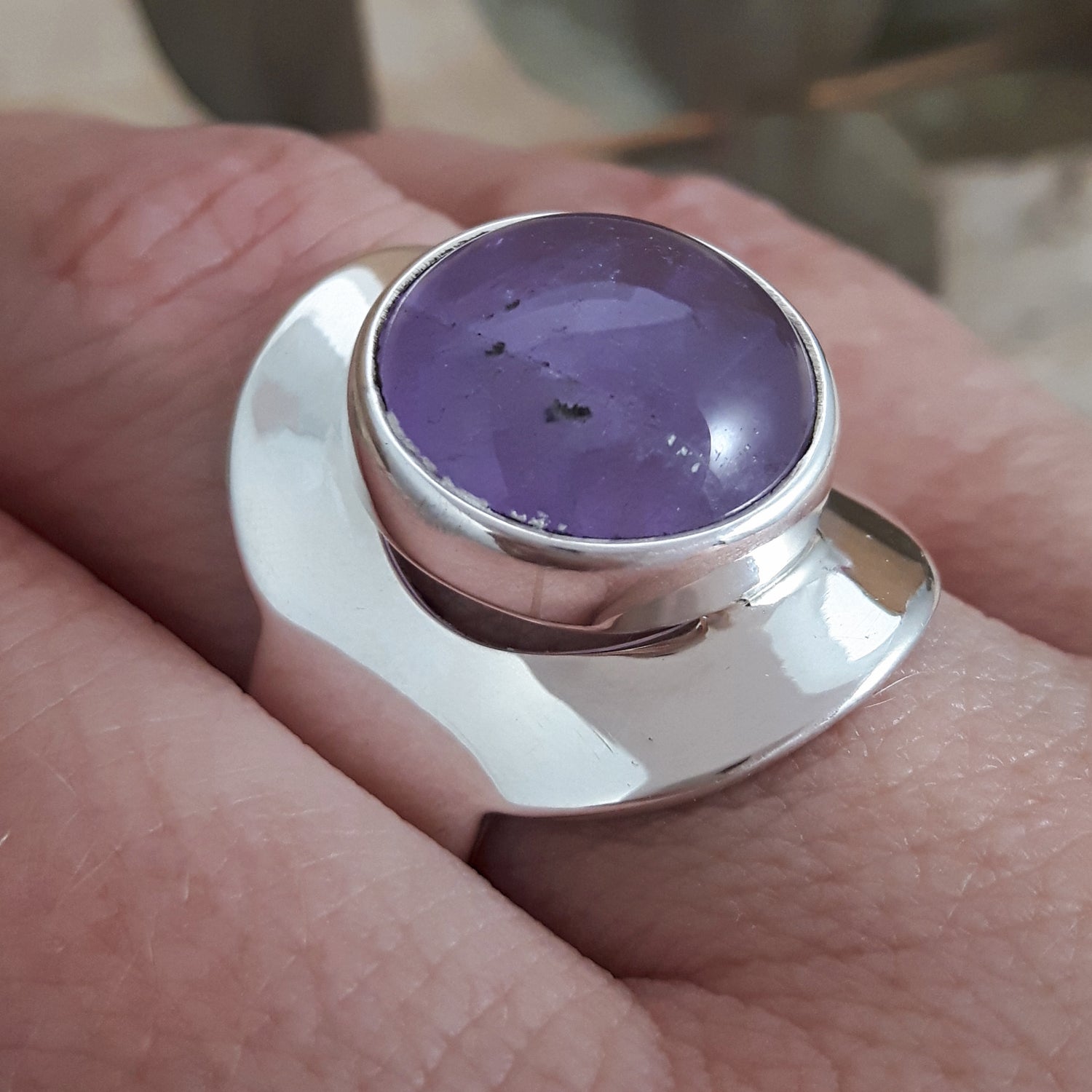 Handmade sterling silver adjustable ring with a purple amethyst gemstone on a hand
