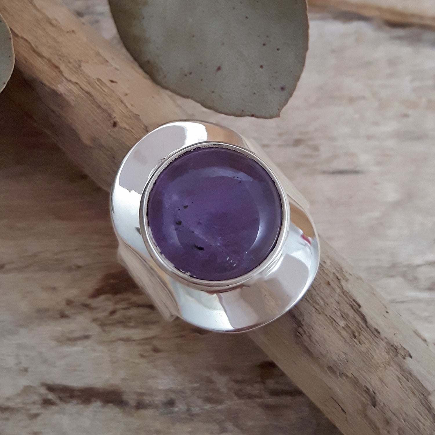 Handcrafted sterling silver ring with an amethyst gemstone on a wooden surface