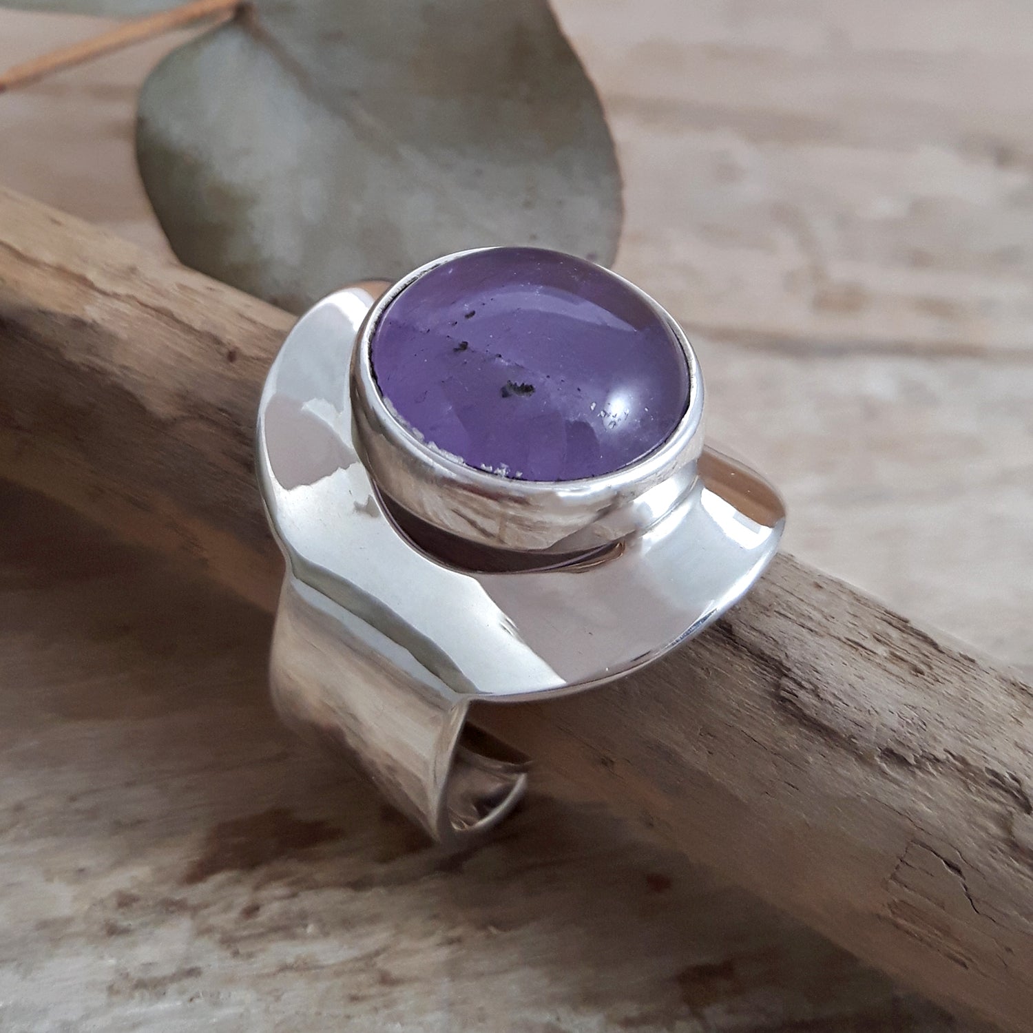 Sterling silver ring with a purple amethyst gemstone on a wooden surface