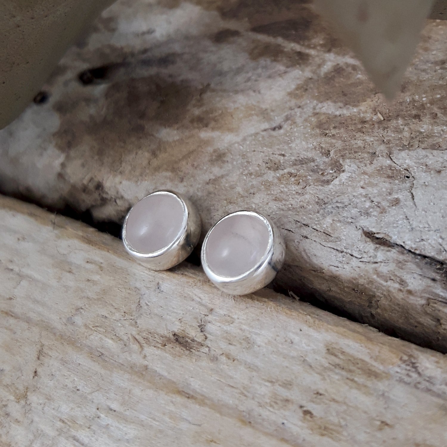 Sterling silver earrings with rose quartz stones on a stone surface