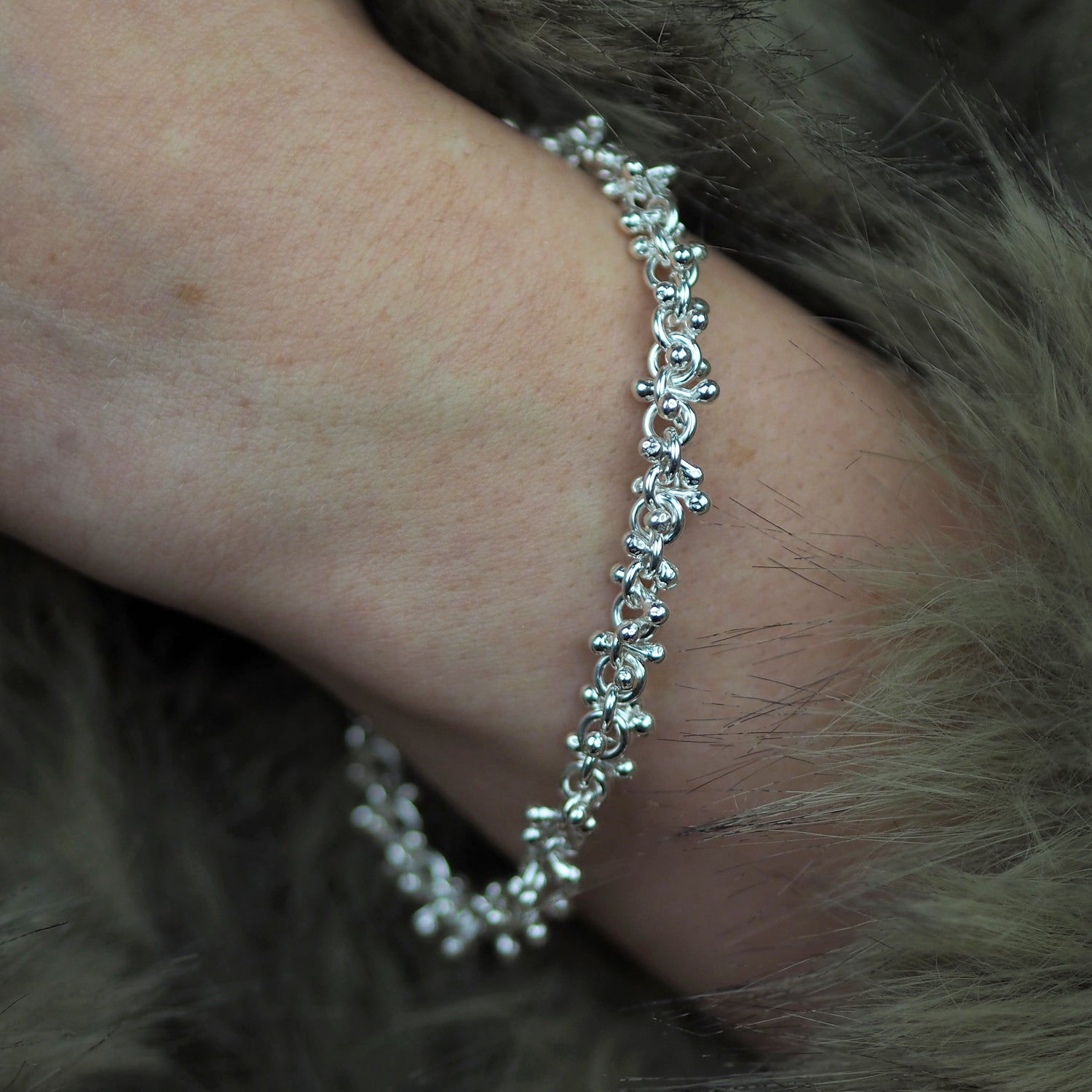 Silver bracelet on a wrist with a fur background