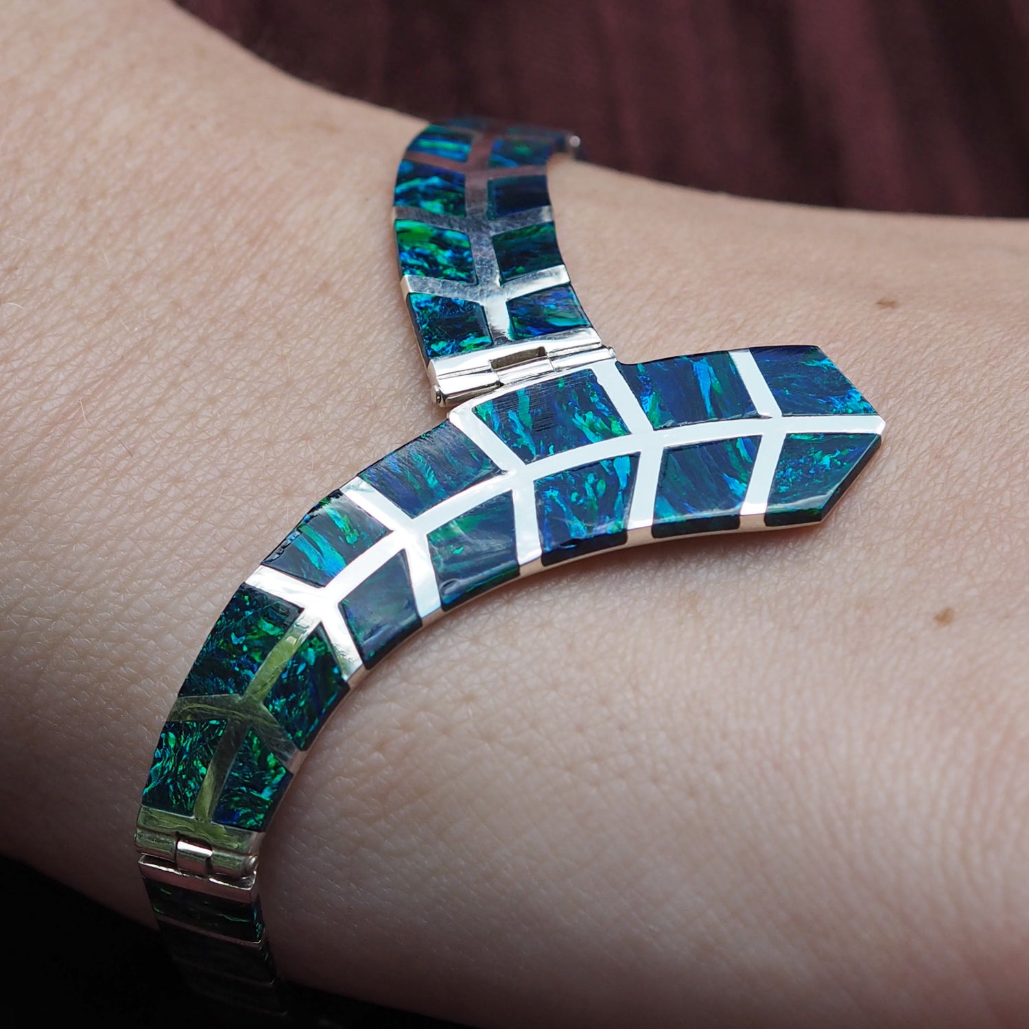 Flinder emerald cultured opal bracelet on a wrist with a blurred background