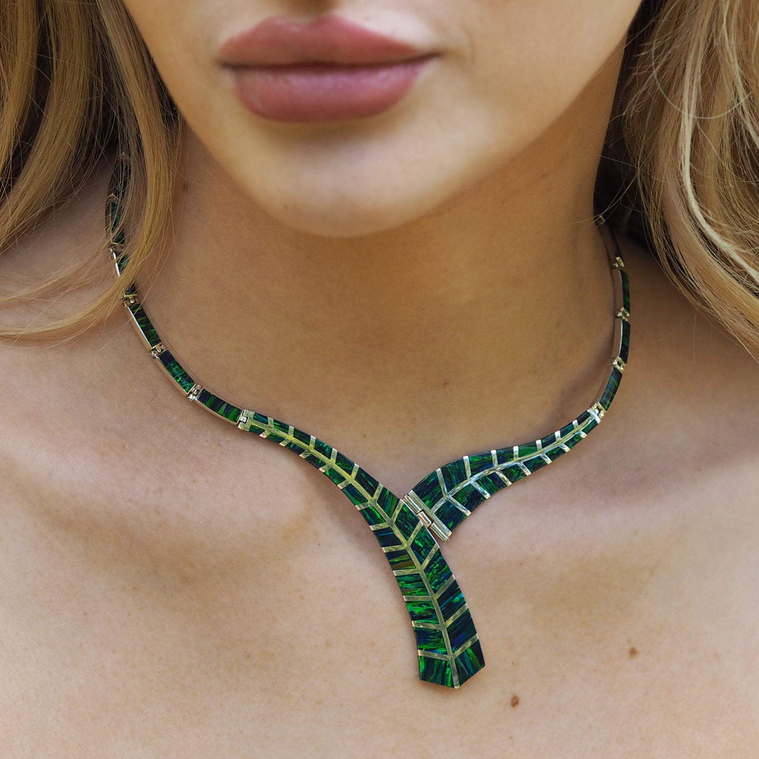 Close-up of a person wearing a Flinder Rio emerald cultured opal leaf-shaped necklace.
