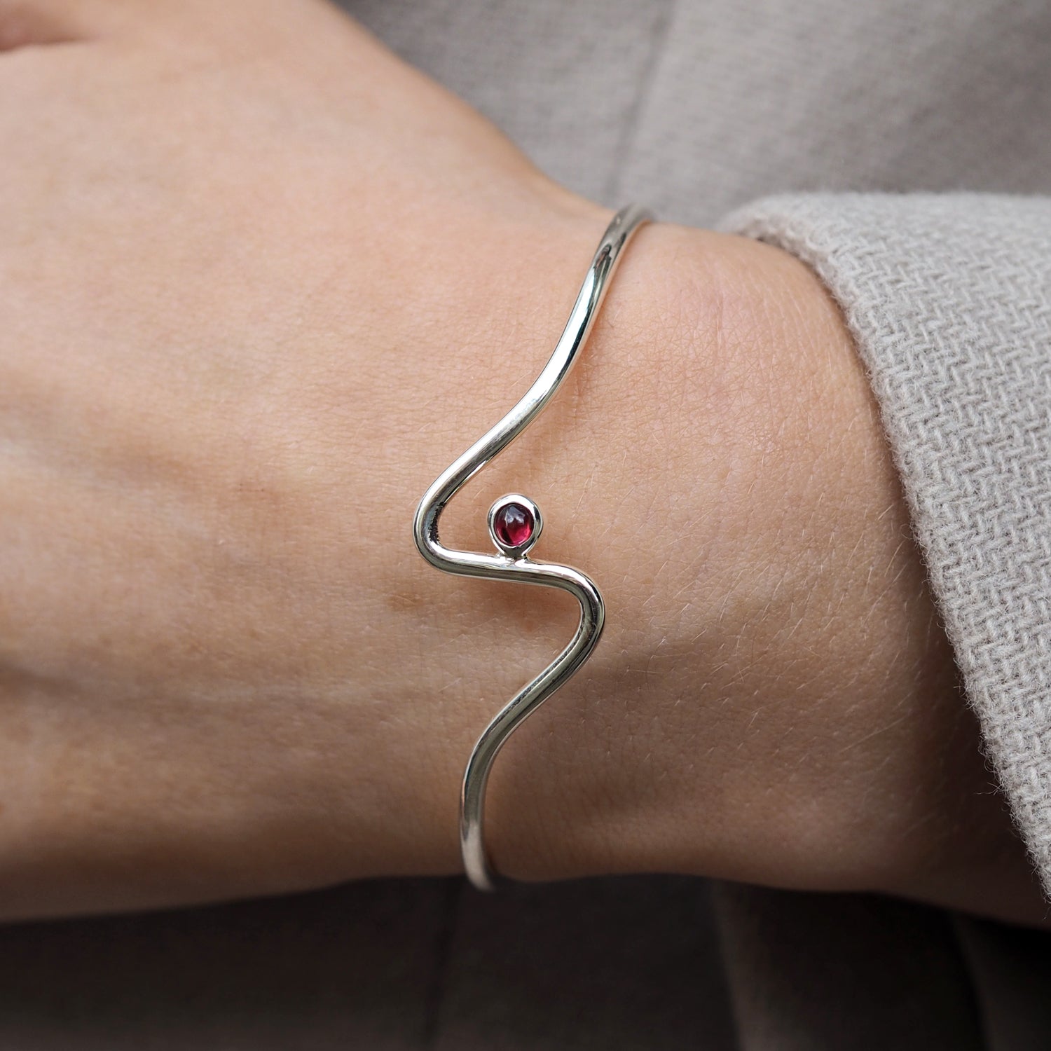 Silver bracelet with a red garnet gemstone on a wrist