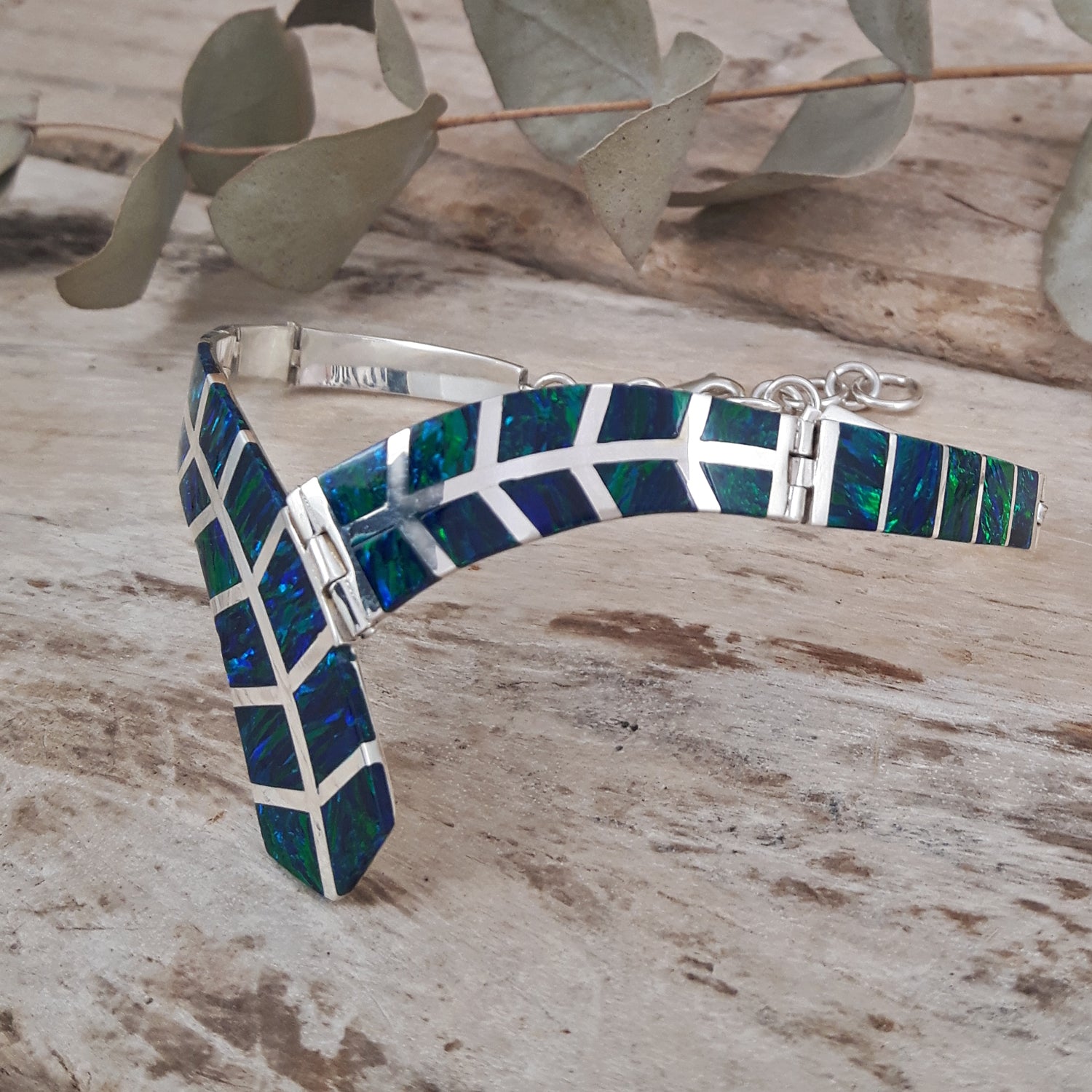 Emerald cultured opal and sterling silver ladies bracelet on a wooden surface with leaves in the background