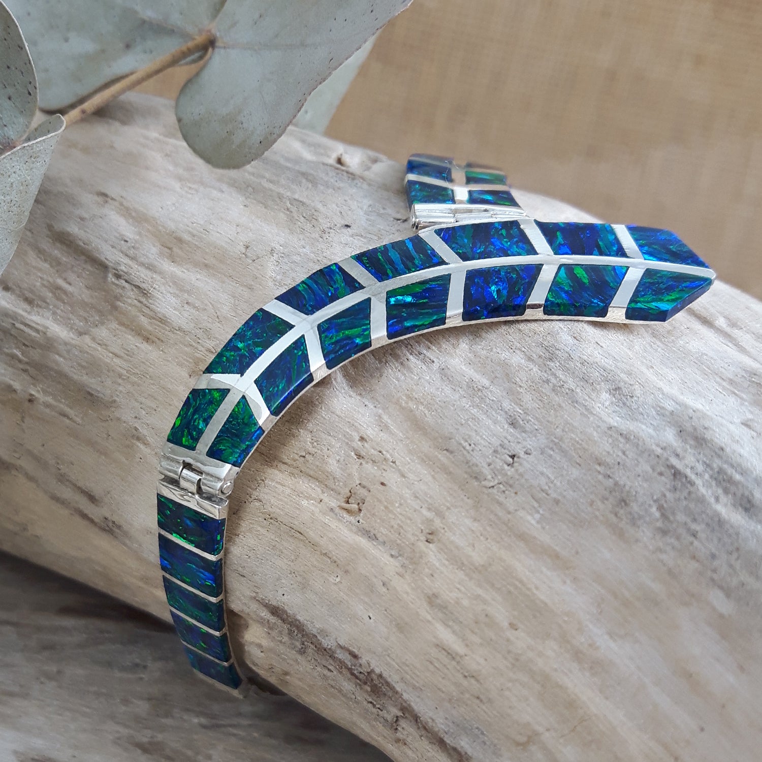 Rio cultured emerald opal and sterling silver bracelet on a wooden surface