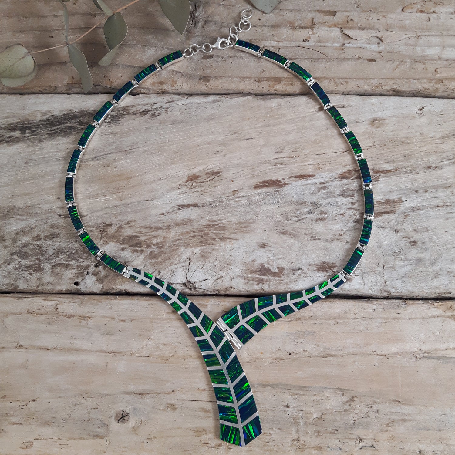 925 sterling silver necklace with emerald cultured opal on a wooden surface
