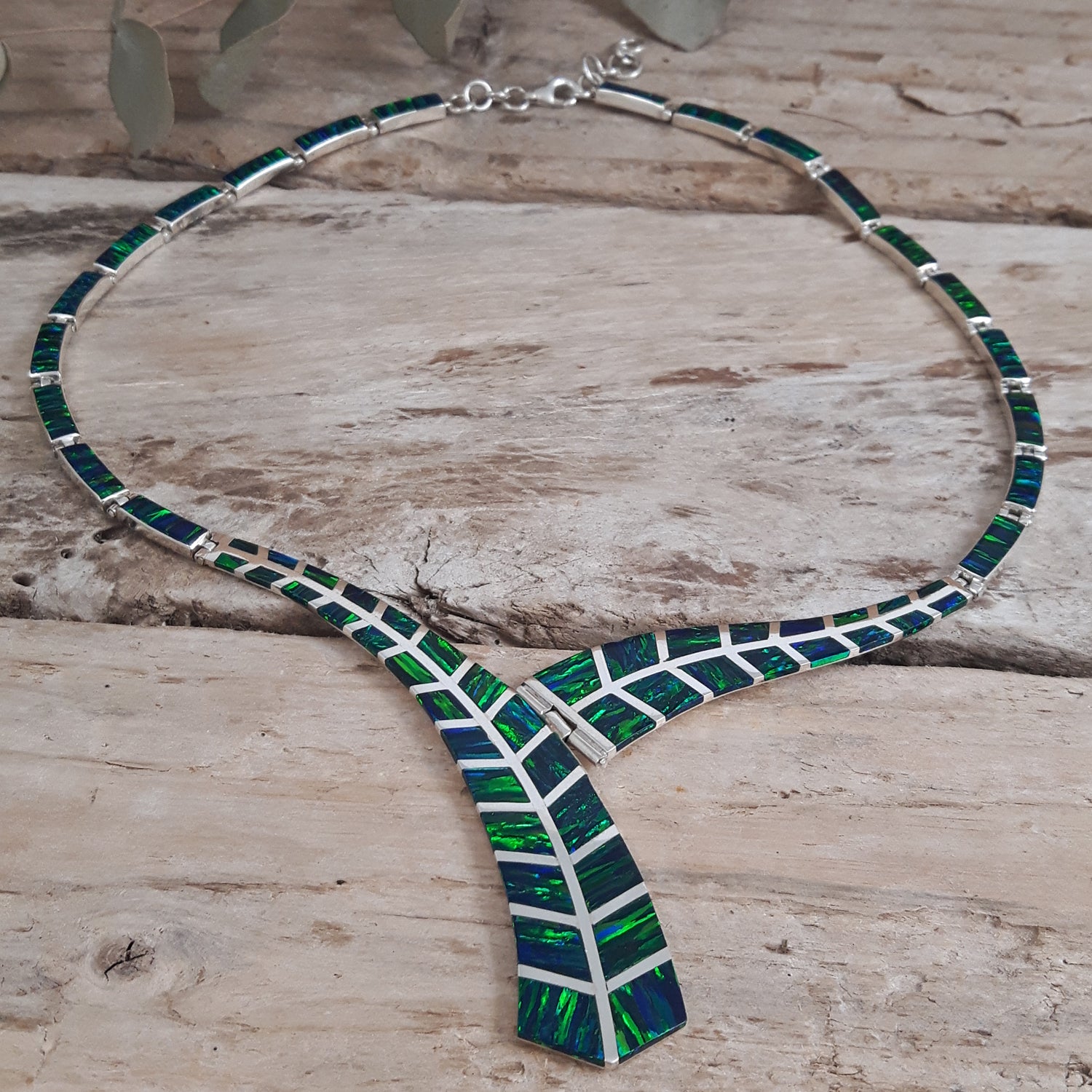 Rio sterling silver necklace with emerald cultured opal on a wooden surface