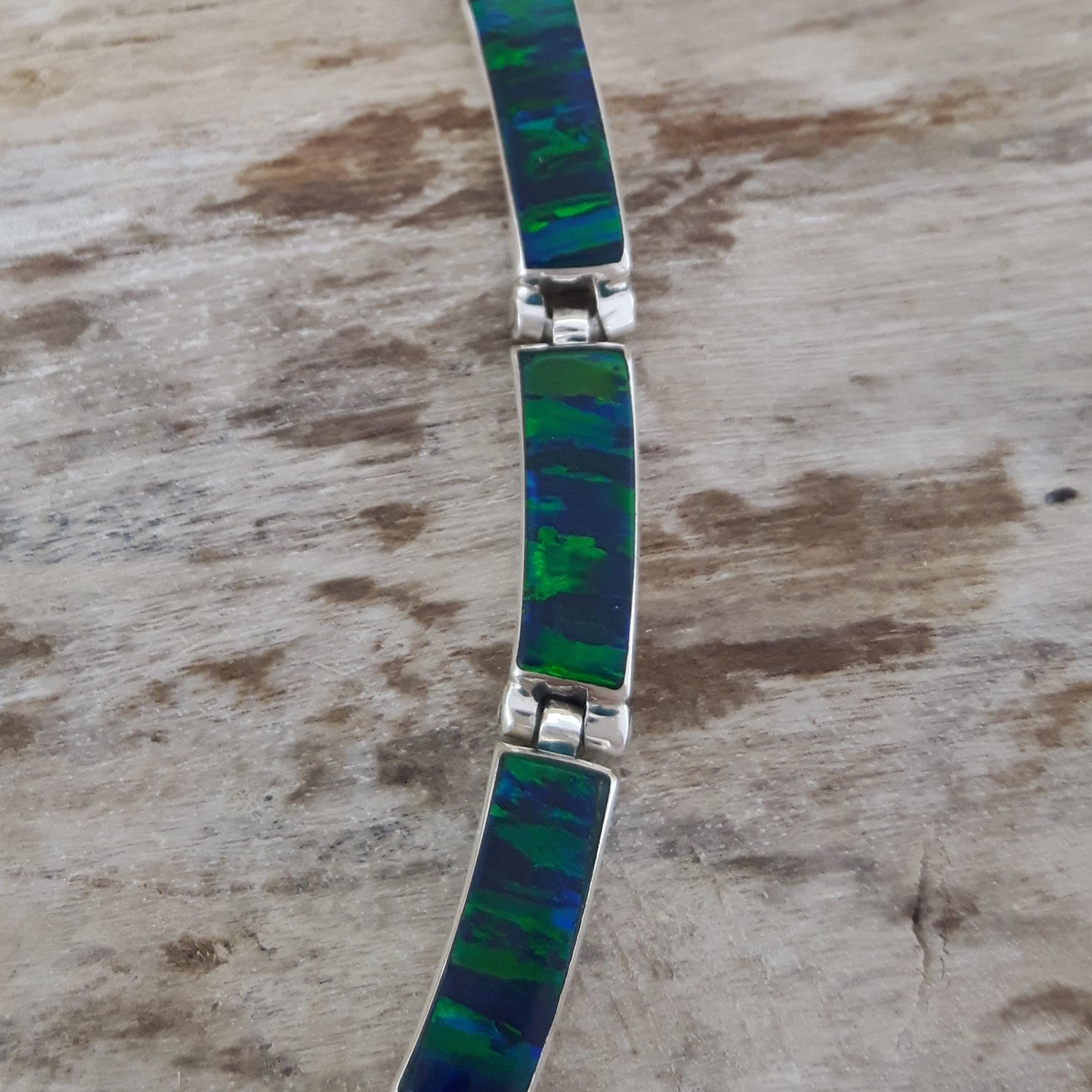Necklace with emerald cultured opal inlay on a wooden surface