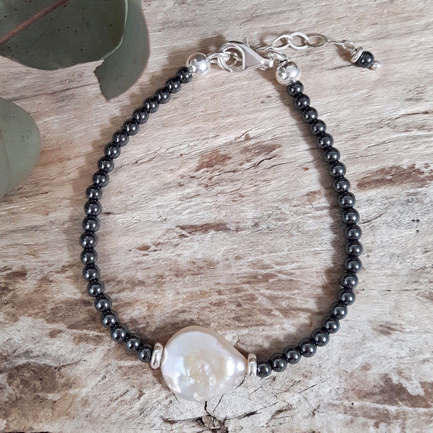 Bracelet with hematite beads and a large white pearl on a wooden surface. UK gift ideas