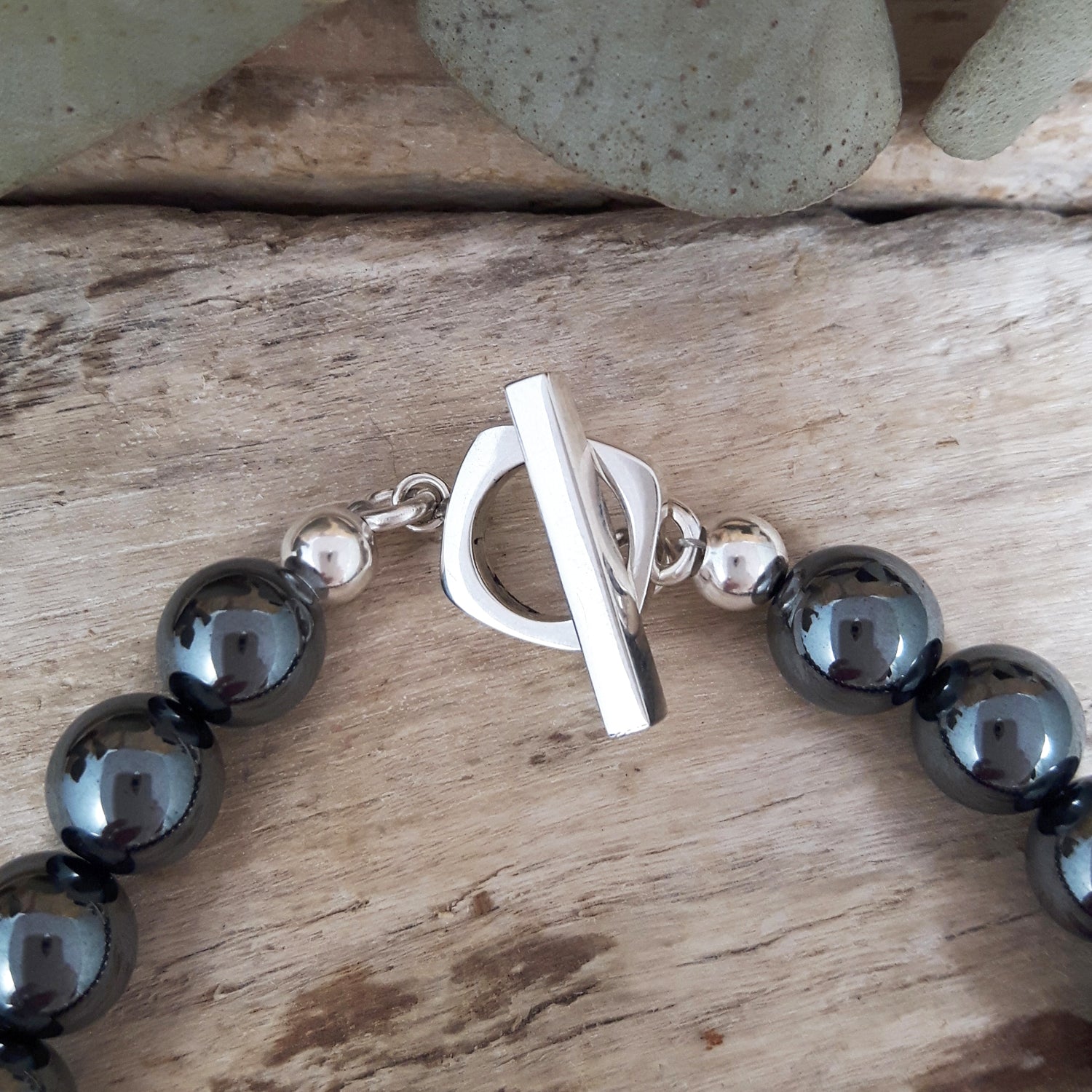 Black beaded bracelet with a sterling silver t-bar on a wooden surface