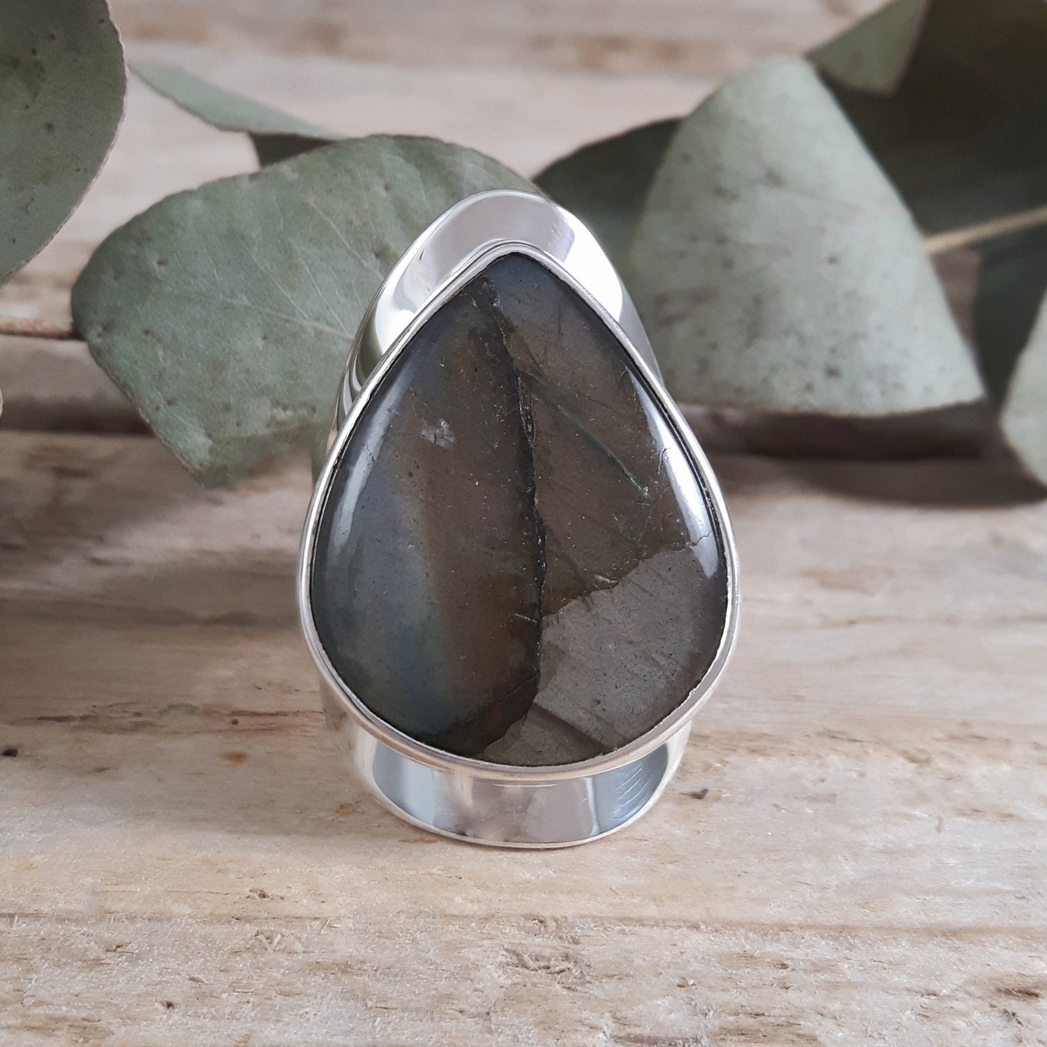 Large Labradorite Handmade Ring on a wooden background.