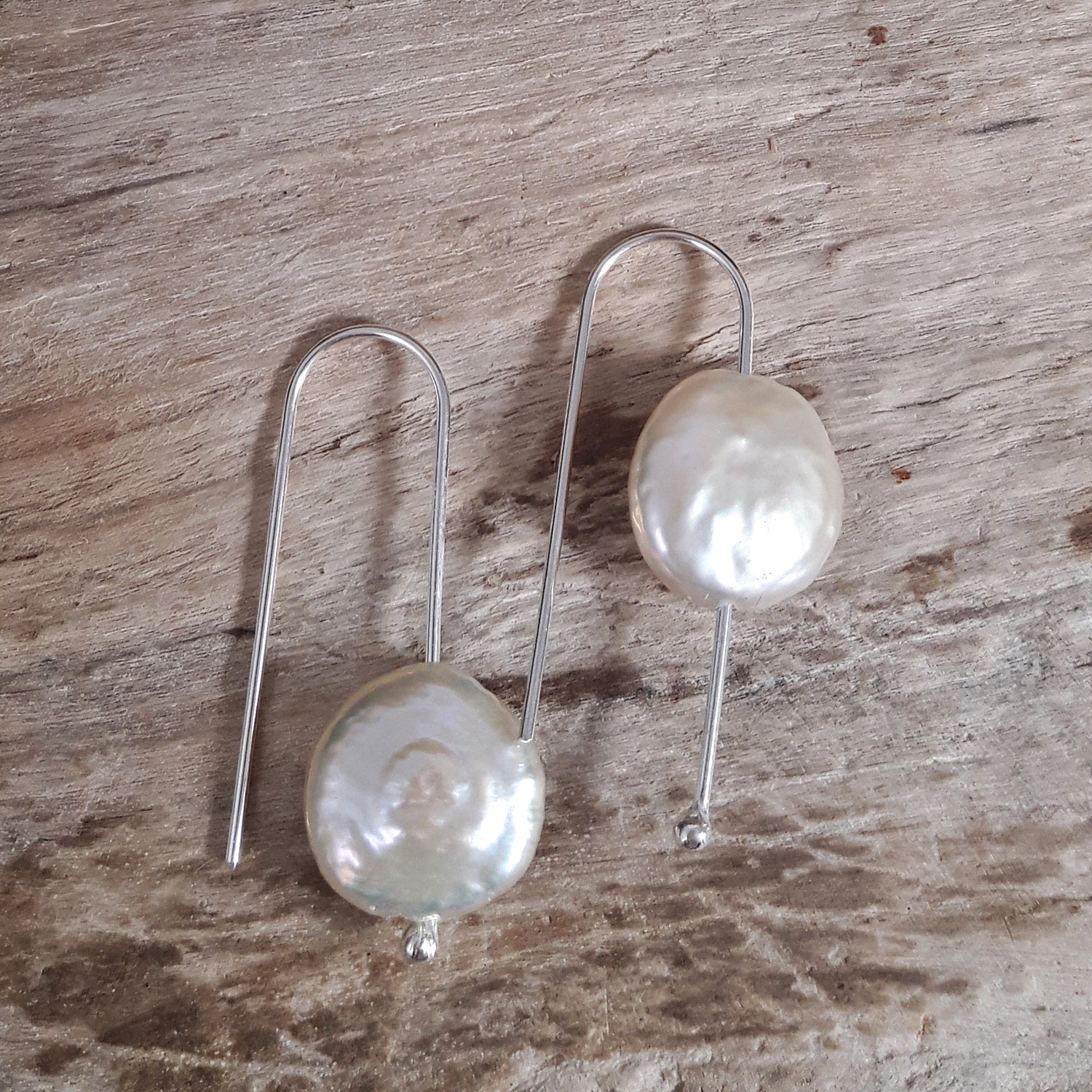 Pair of baroque pearl earrings on a wooden surface