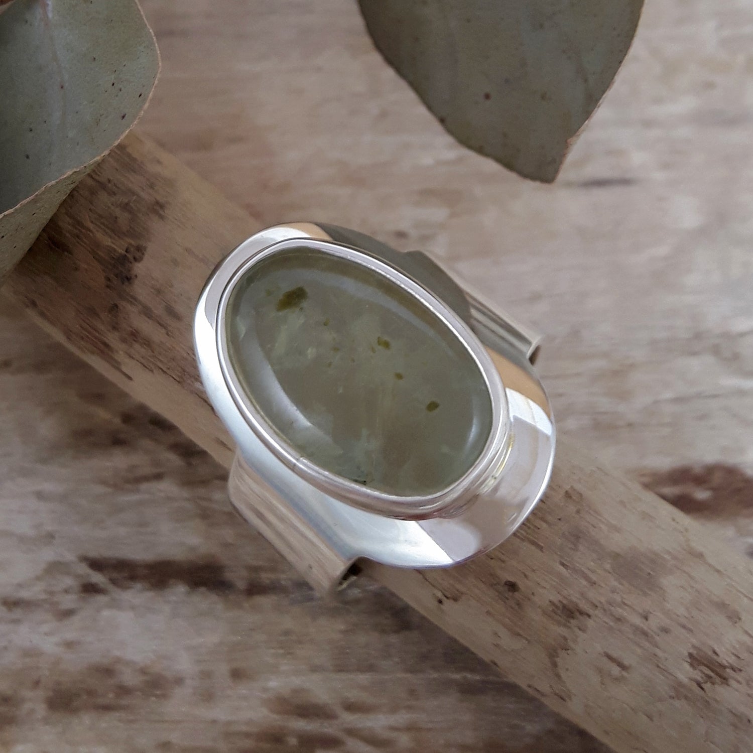 Sterling silver ring with a green prehnite gemstone on a wooden surface