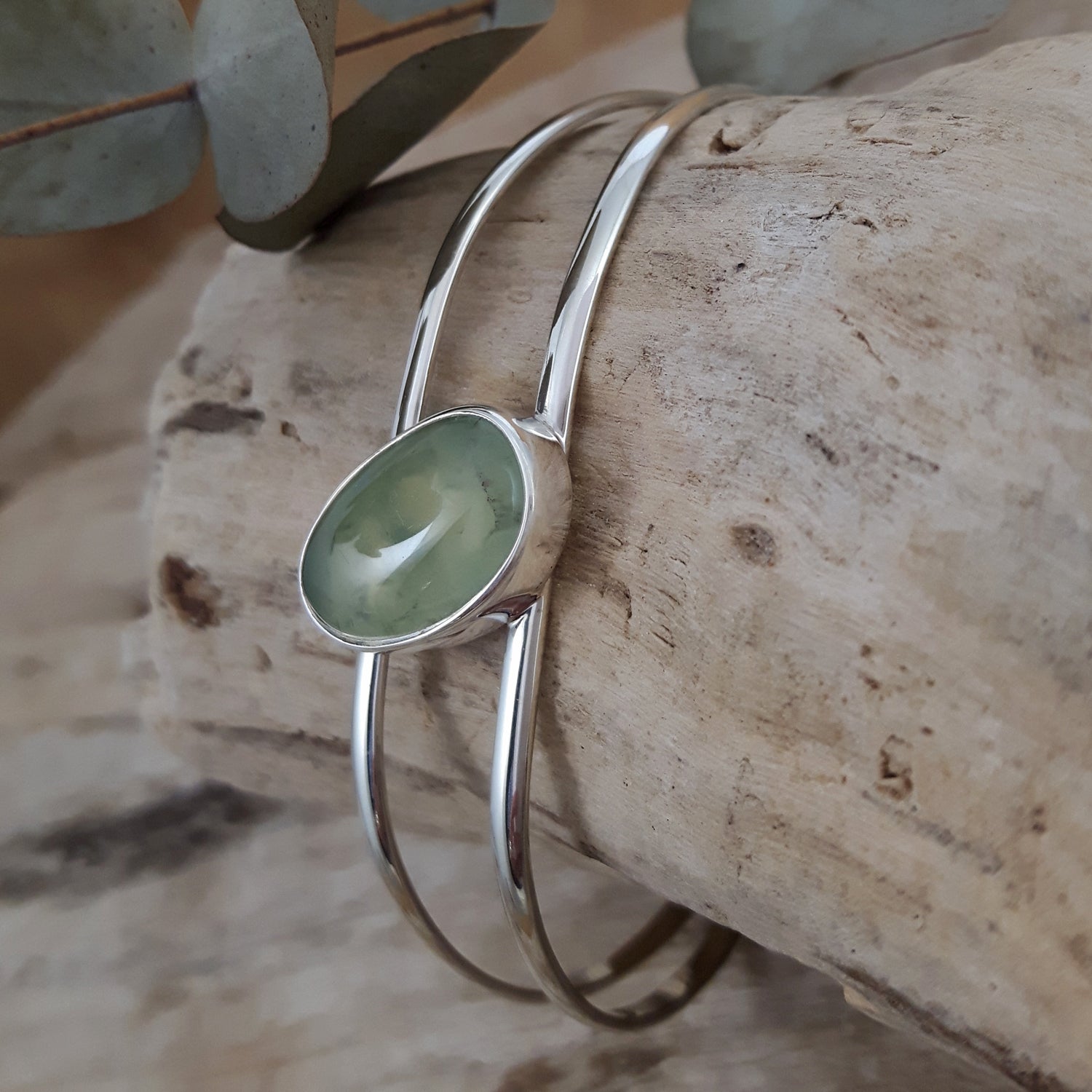 Sterling silver bracelet with a green prehnite gemstone on a wooden surface