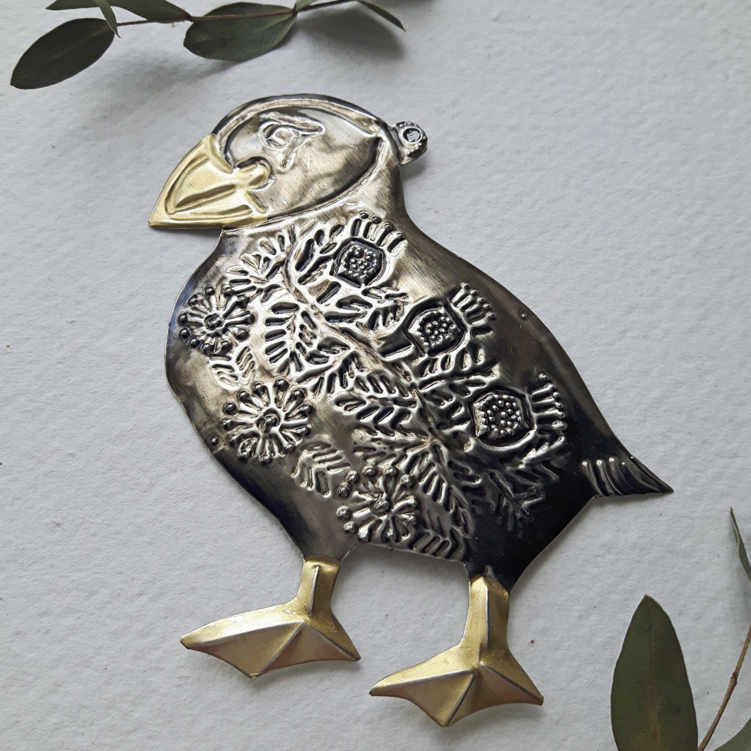 Decorative metal bird ornament on a light gray background