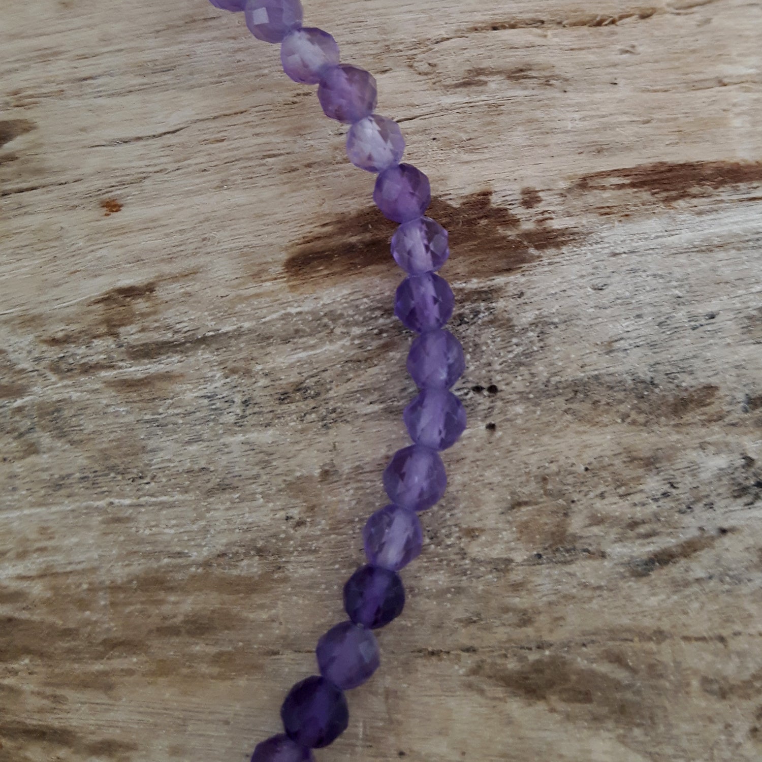 Amethyst beaded necklace on a wooden surface