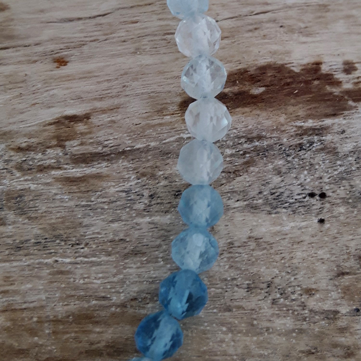 String of aquamarine beads on a wooden surface