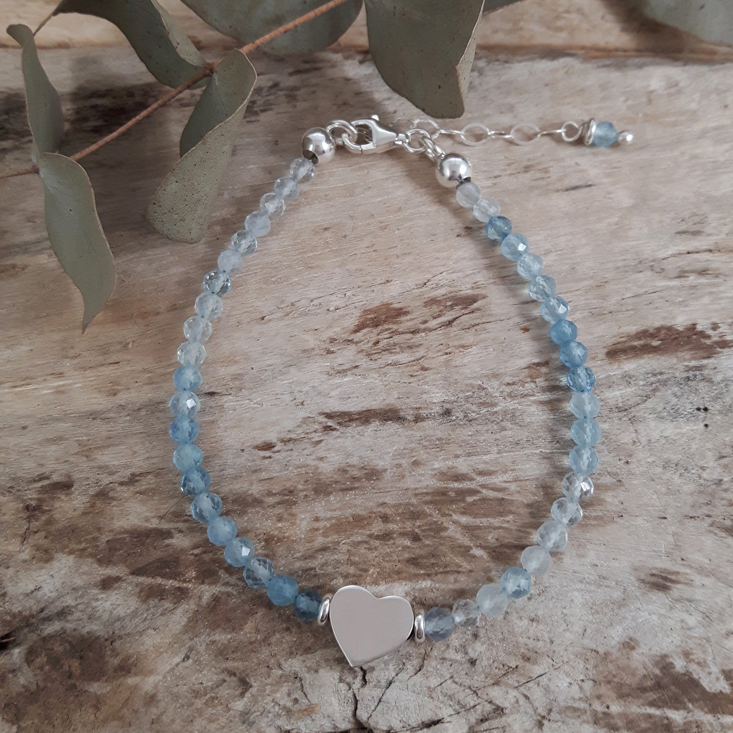 Sterling silver bracelet with heart charm on a wooden surface