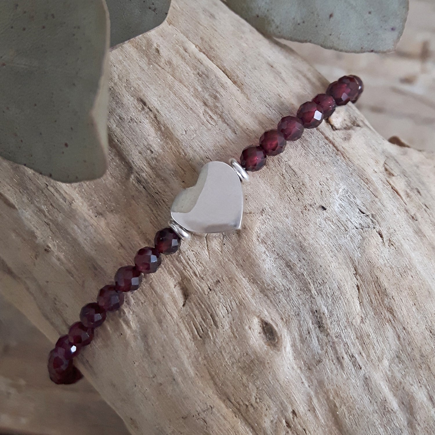 Garnet beaded bracelet with a silver clasp on a wooden surface