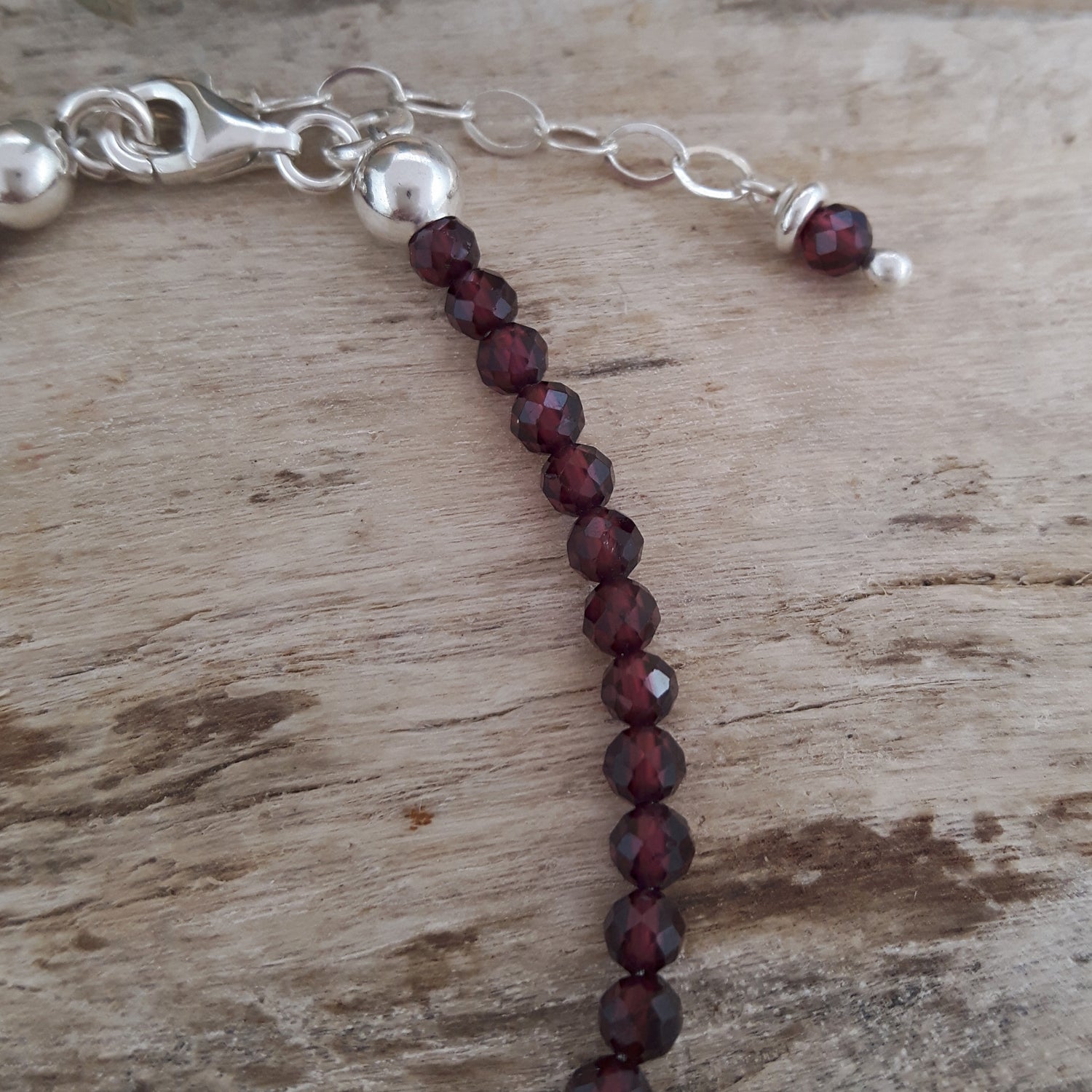 Bracelet with garnet beads and silver clasp on a wooden surface