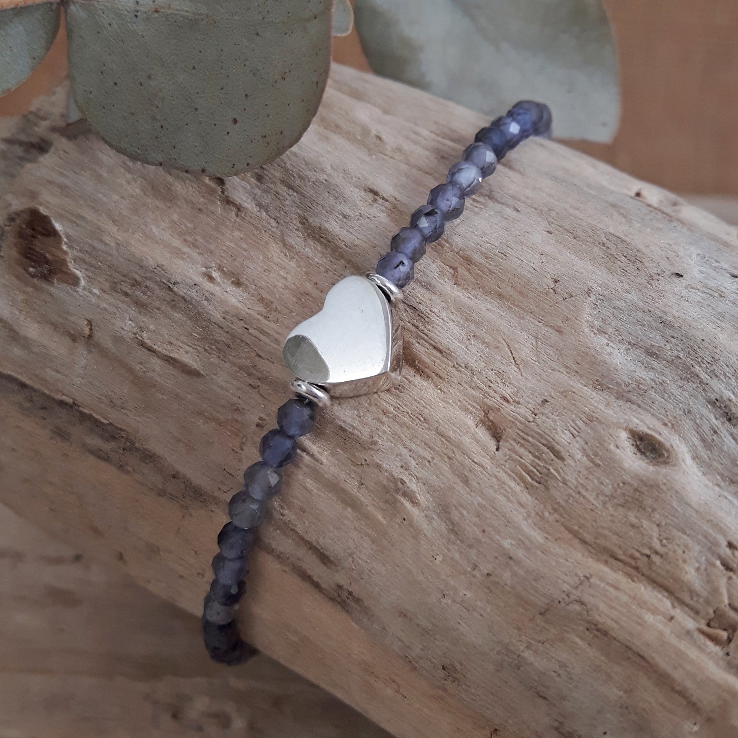 Iolite bracelet with sterling silver heart-shaped charm on a wooden surface