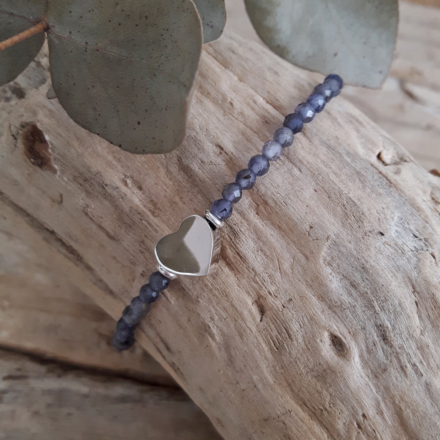 Iolite birthstone bracelet with sterling silver heart charm on a wooden surface