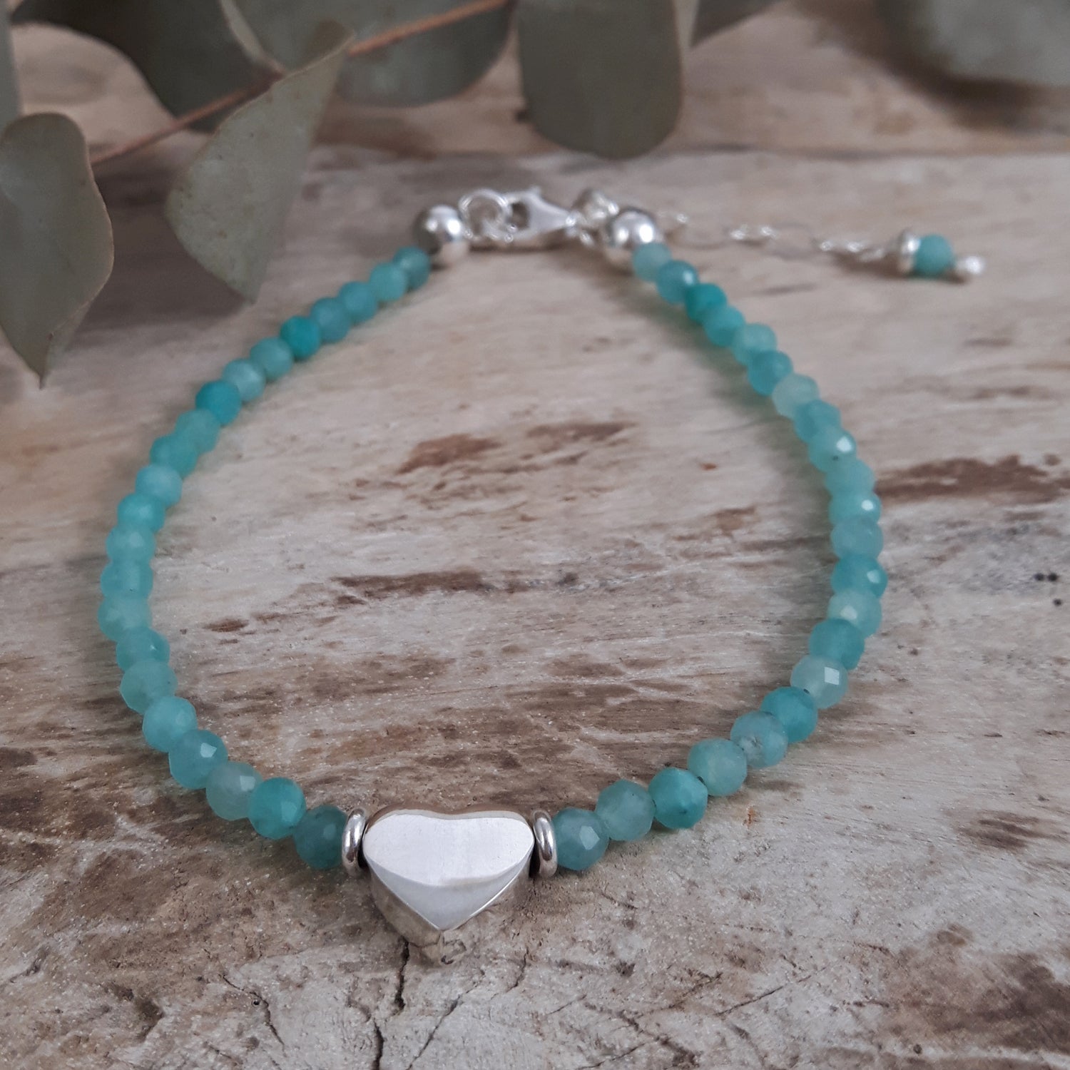 Amazonite beaded bracelet with a sterling silver heart-shaped charm on a wooden surface