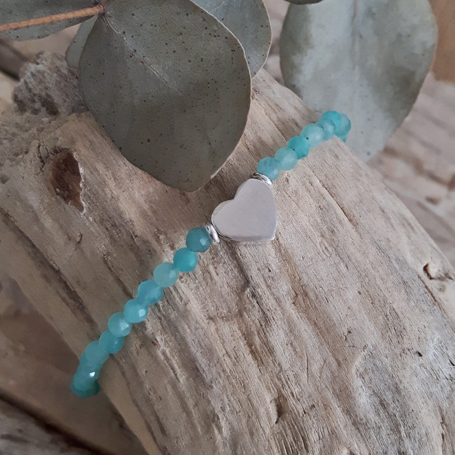 Amazonite beaded bracelet with a sterling silver heart charm on a wooden surface.