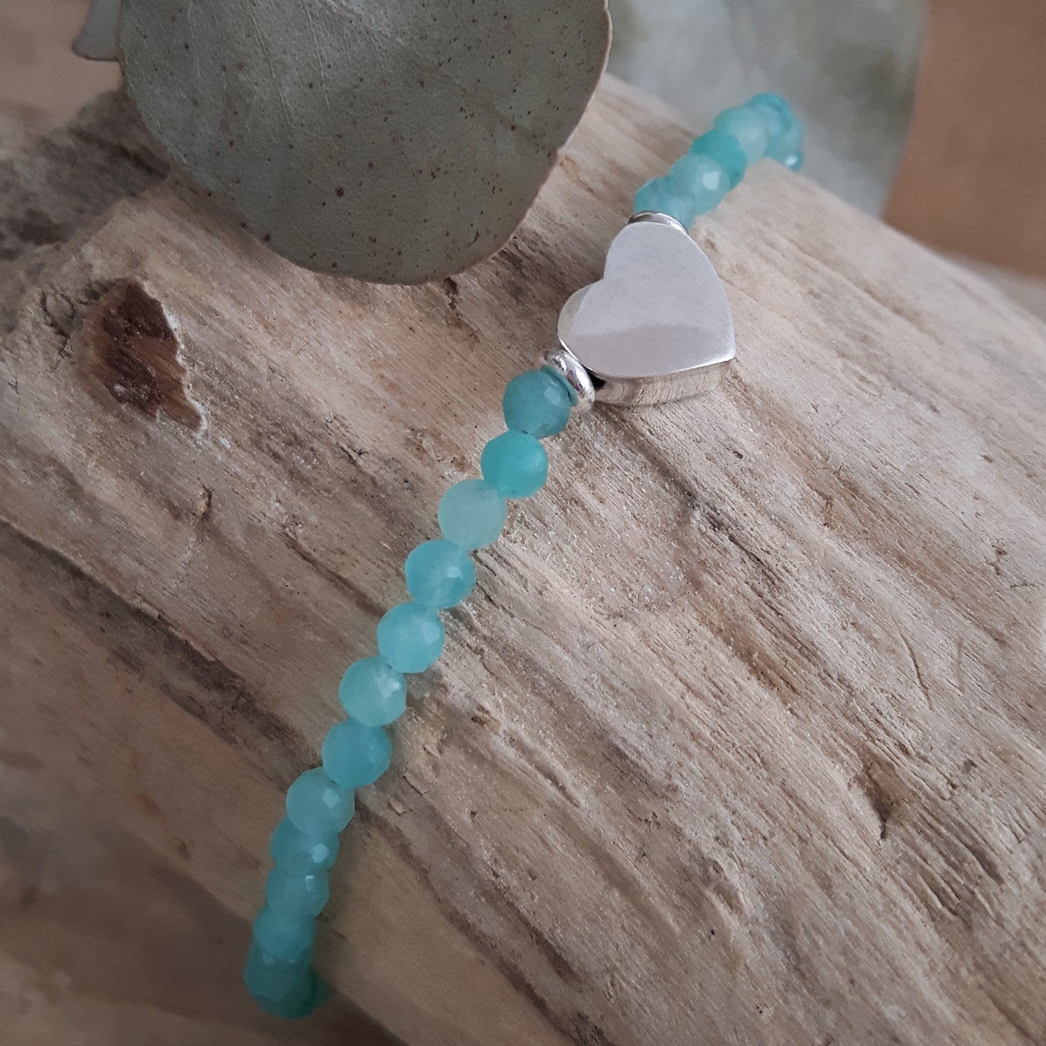 Amazonite beaded bracelet with a sterling silver heart charm on a wooden surface