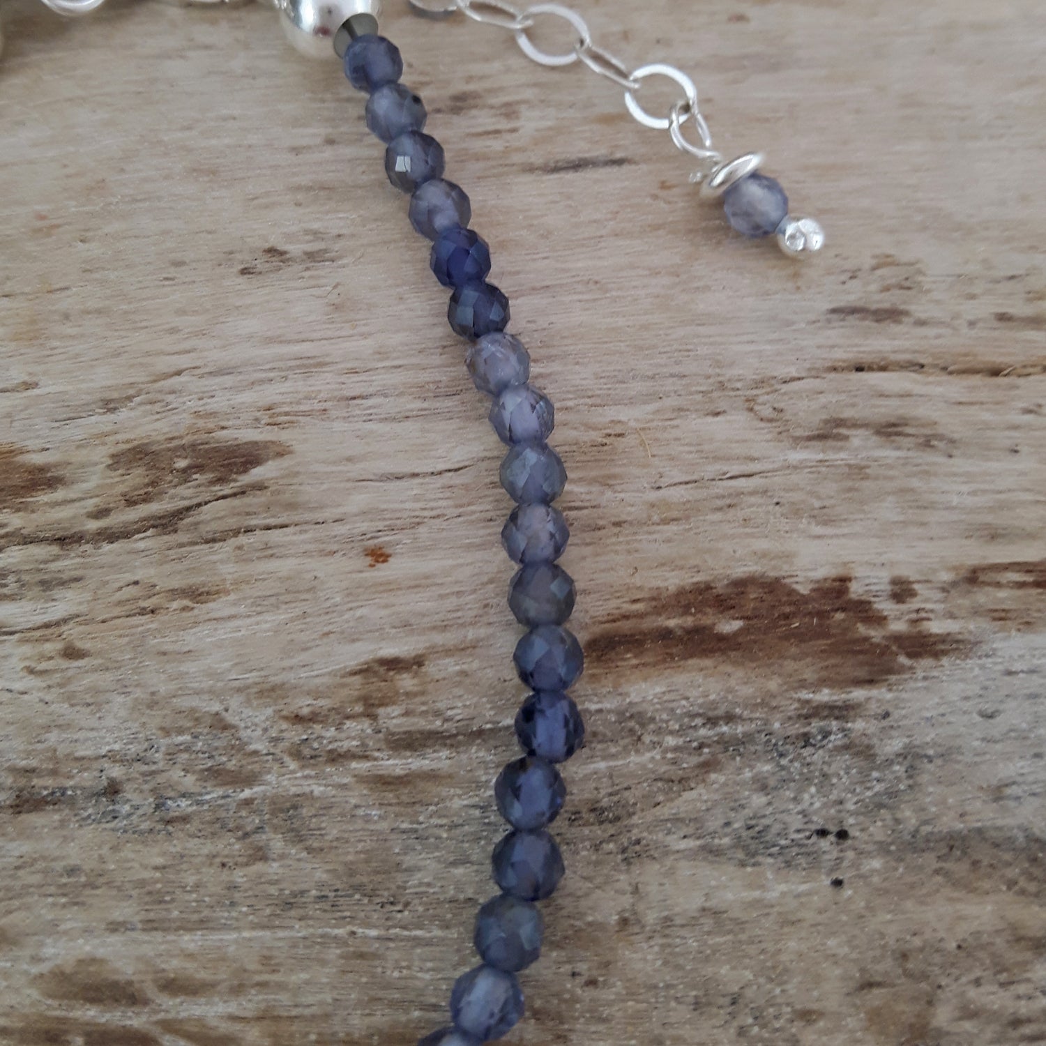 Beaded bracelet with blue iolite beads on a wooden surface